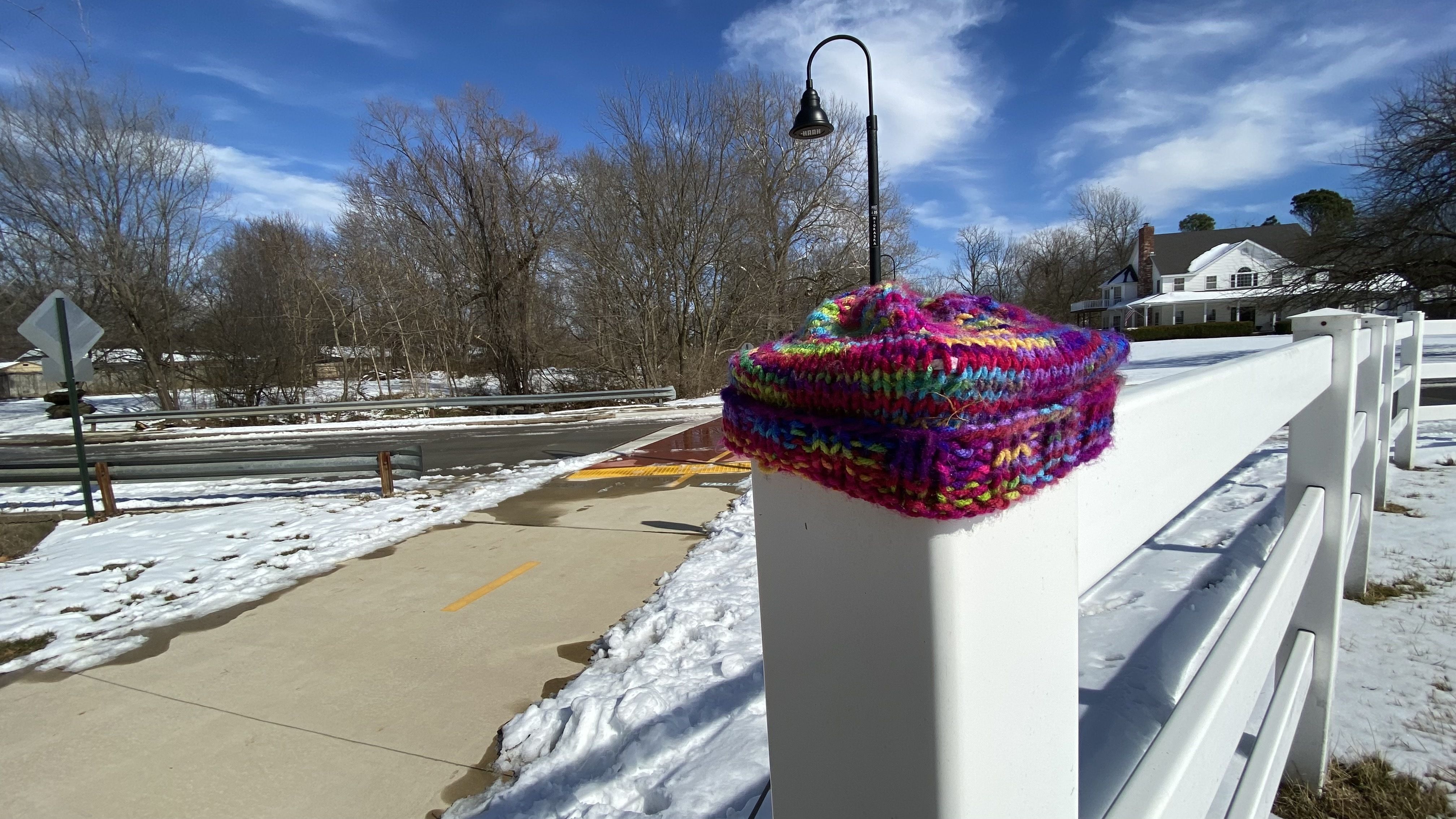 A knit cap sits atop a fence post. 