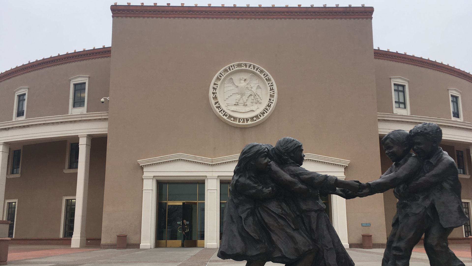 A statue of children in front of the New Mexicop Statehouse.