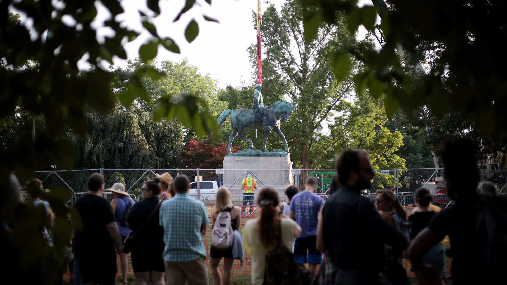 Picture of a crowd watching as a statue gets removed