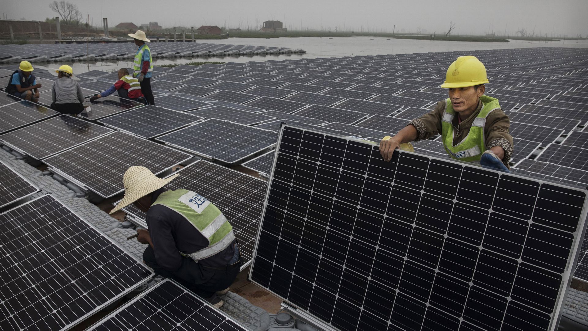 Chinese workers prepare panels that will be part of a large floating solar farm project under construction