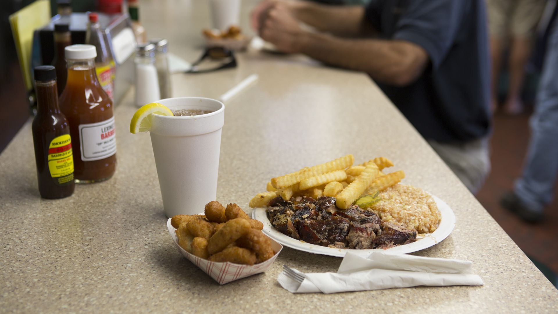 A plate of barbecue and hushpuppies on a counter. 