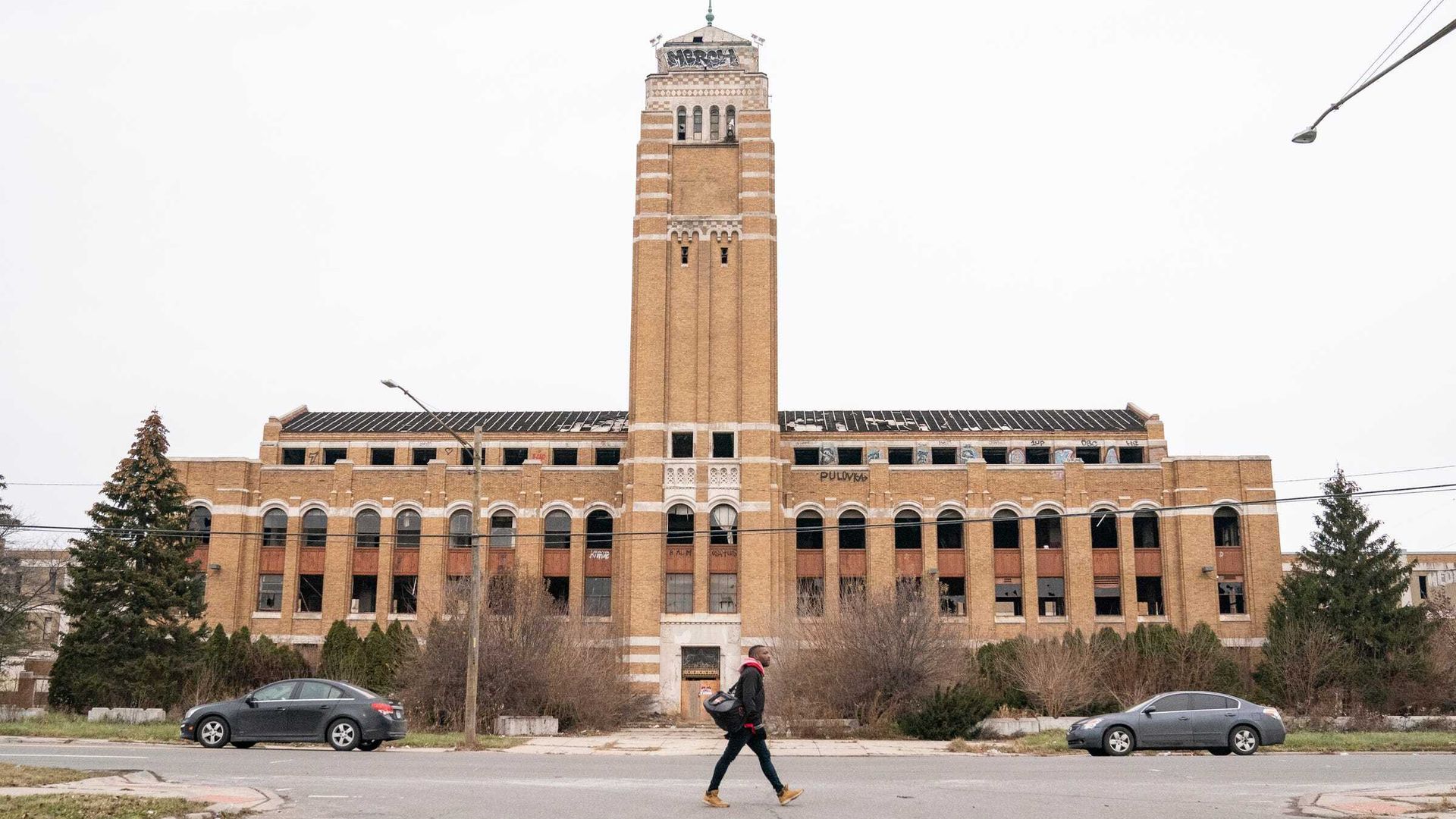 The former AMC headquarters building sits vacant while a person walks in front of it along the street.
