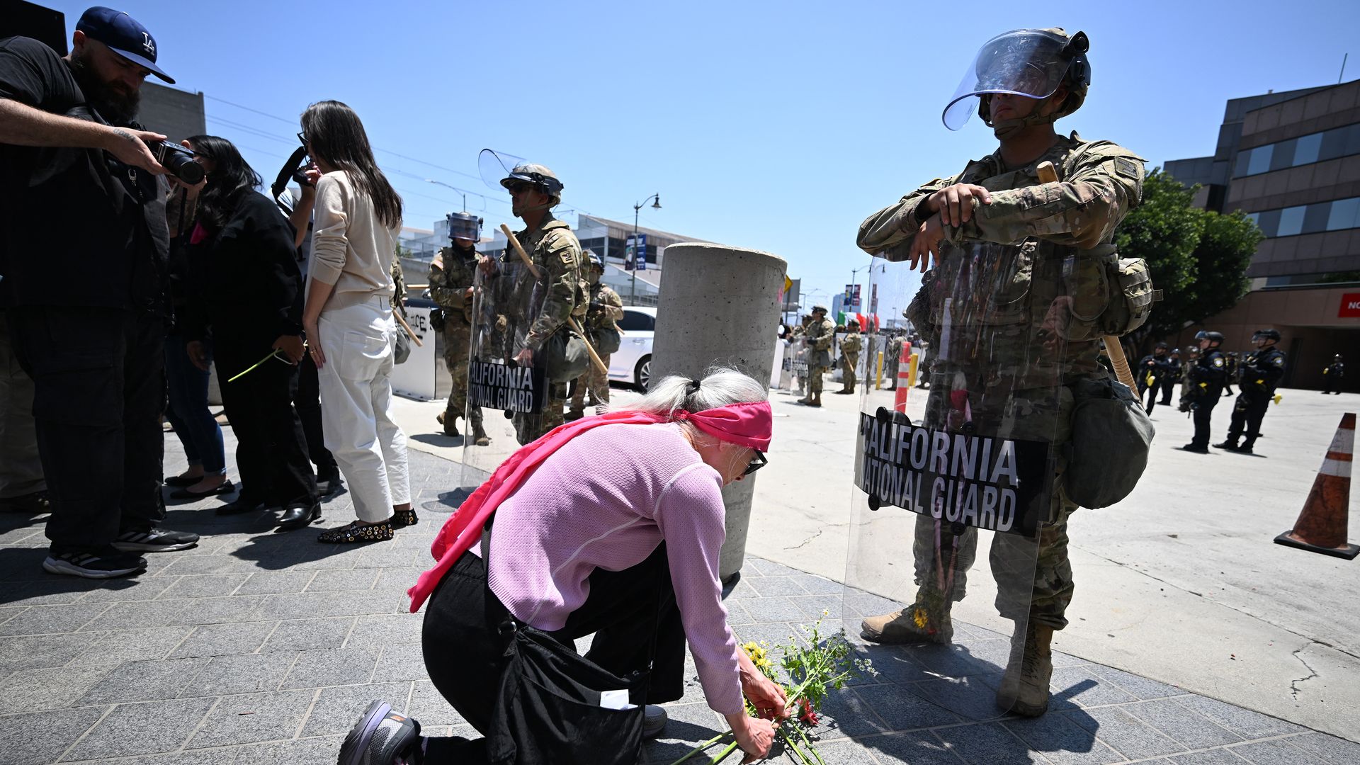 Members of the clergy and other protestors place flowers at the feet of a California National Guardsman stationed outside federal buildings near the Metropolitan Detention Center in Los Angeles on June 10, 2025, amid ongoing protests in response to federal immigration operations. 