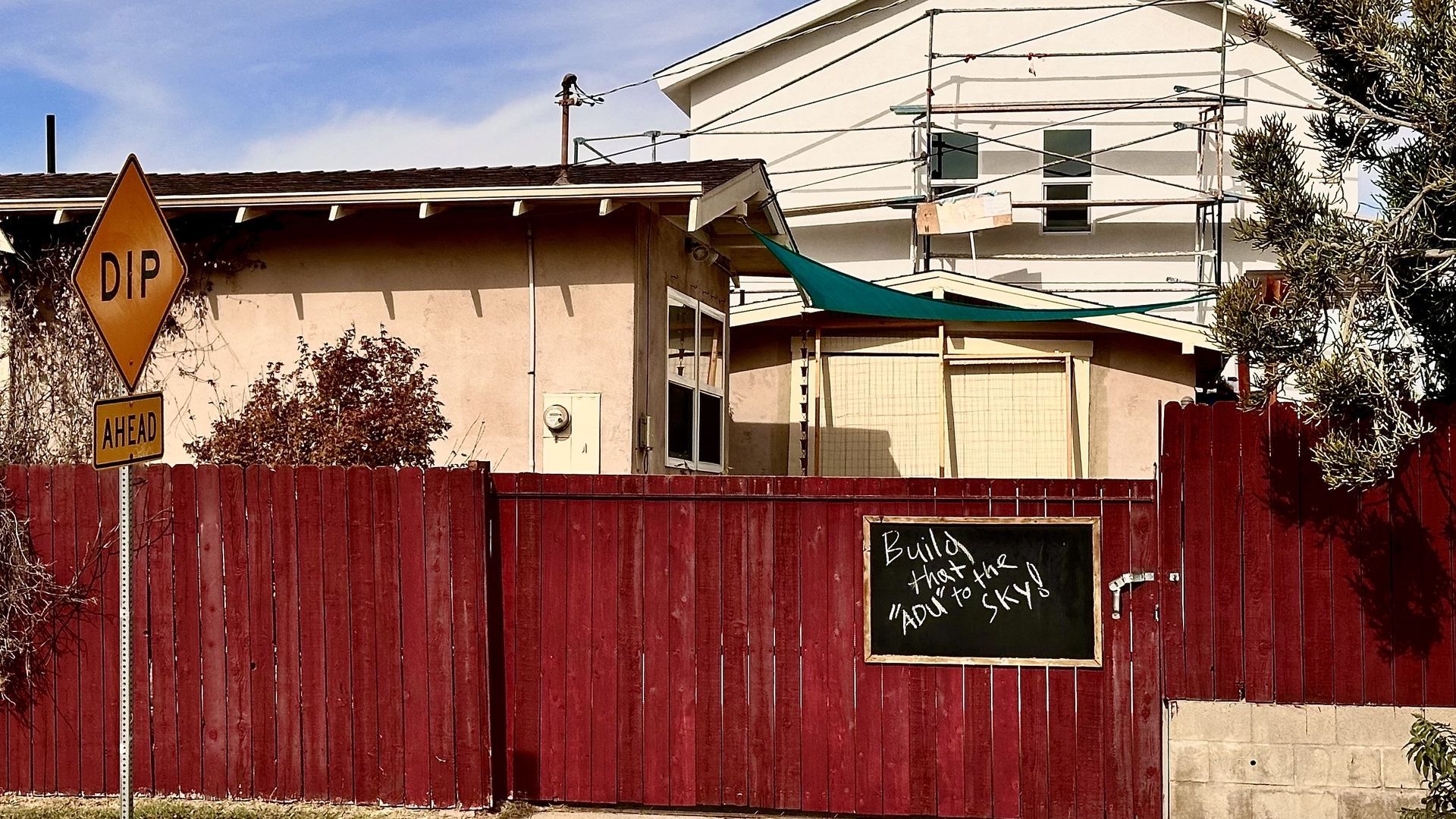 A neighbor's sign reads "build that ADU to the sky," protesting nearby development