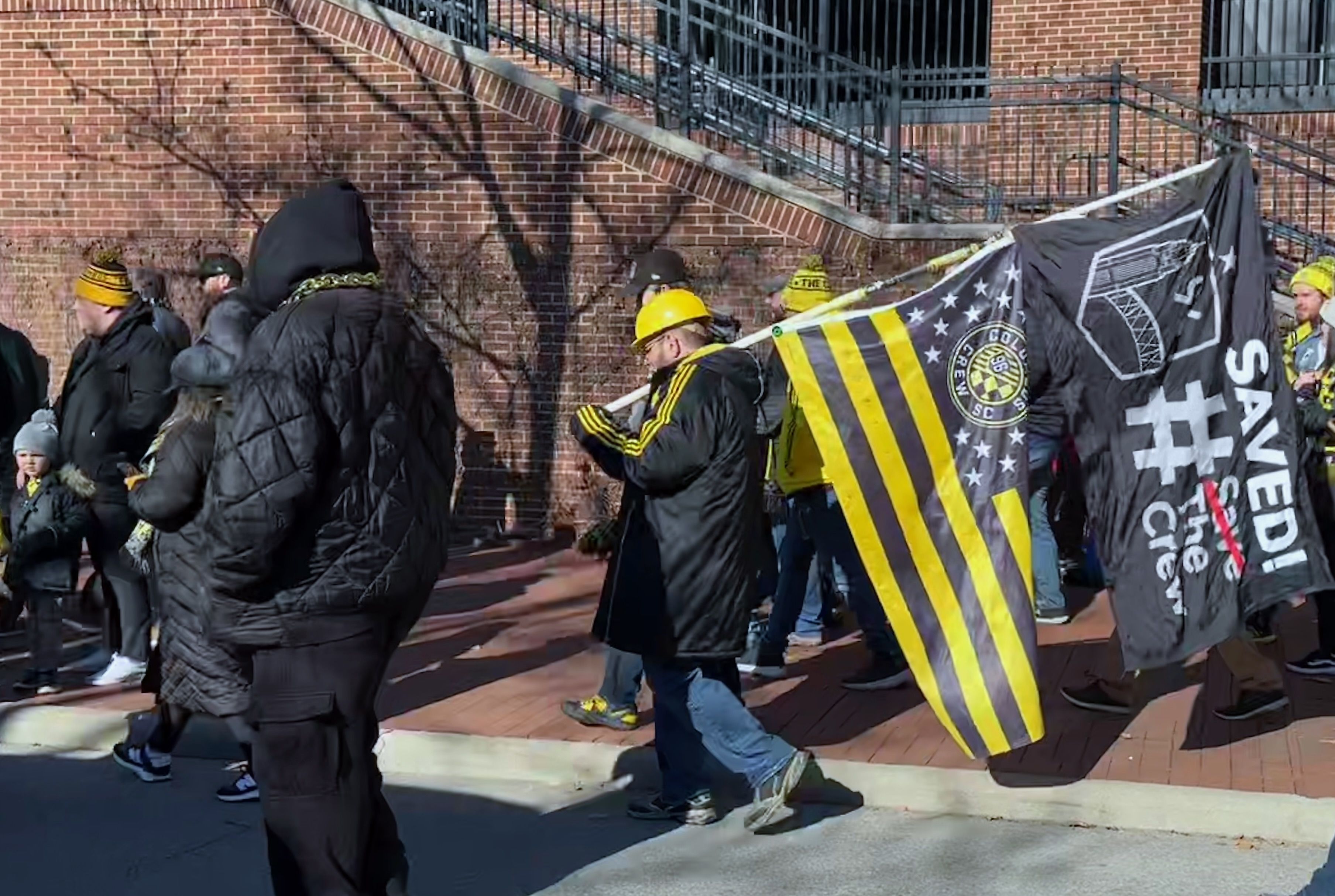 A Crew fan holds a "Saved the Crew" flag while walking down Nationwide Boulevard