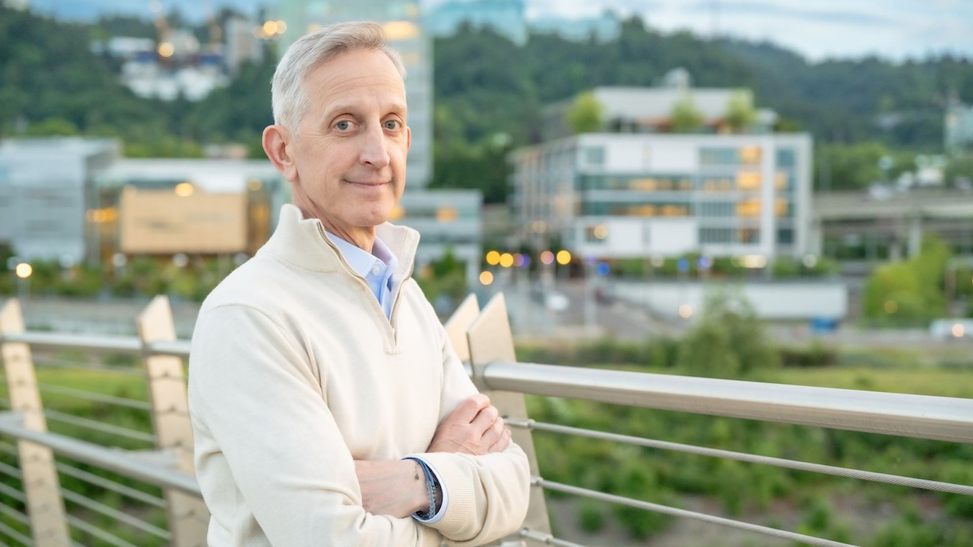 A man poses for a portrait in front of a fence.