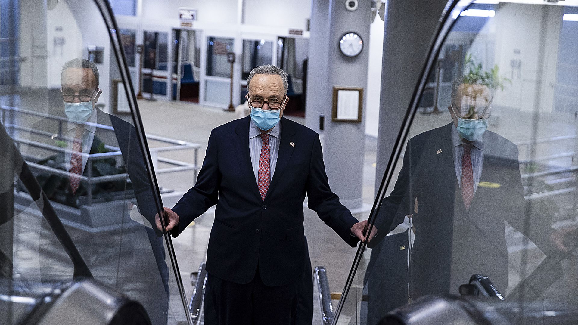 Sen. Chuck Schumer wearing a medical mask and riding up an escalator in the Senate building basement.