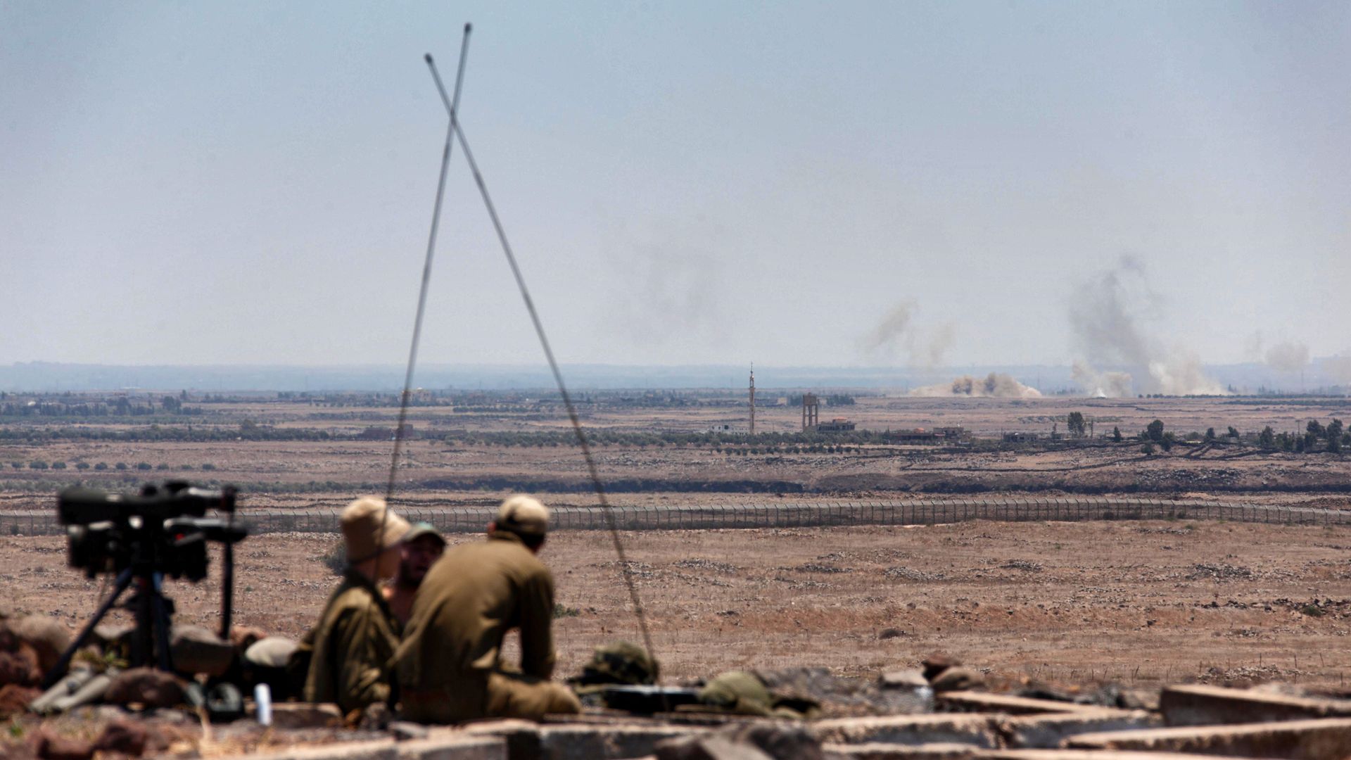 Israeli soldiers in the Golan Heights watch explosions from Syrian fighting