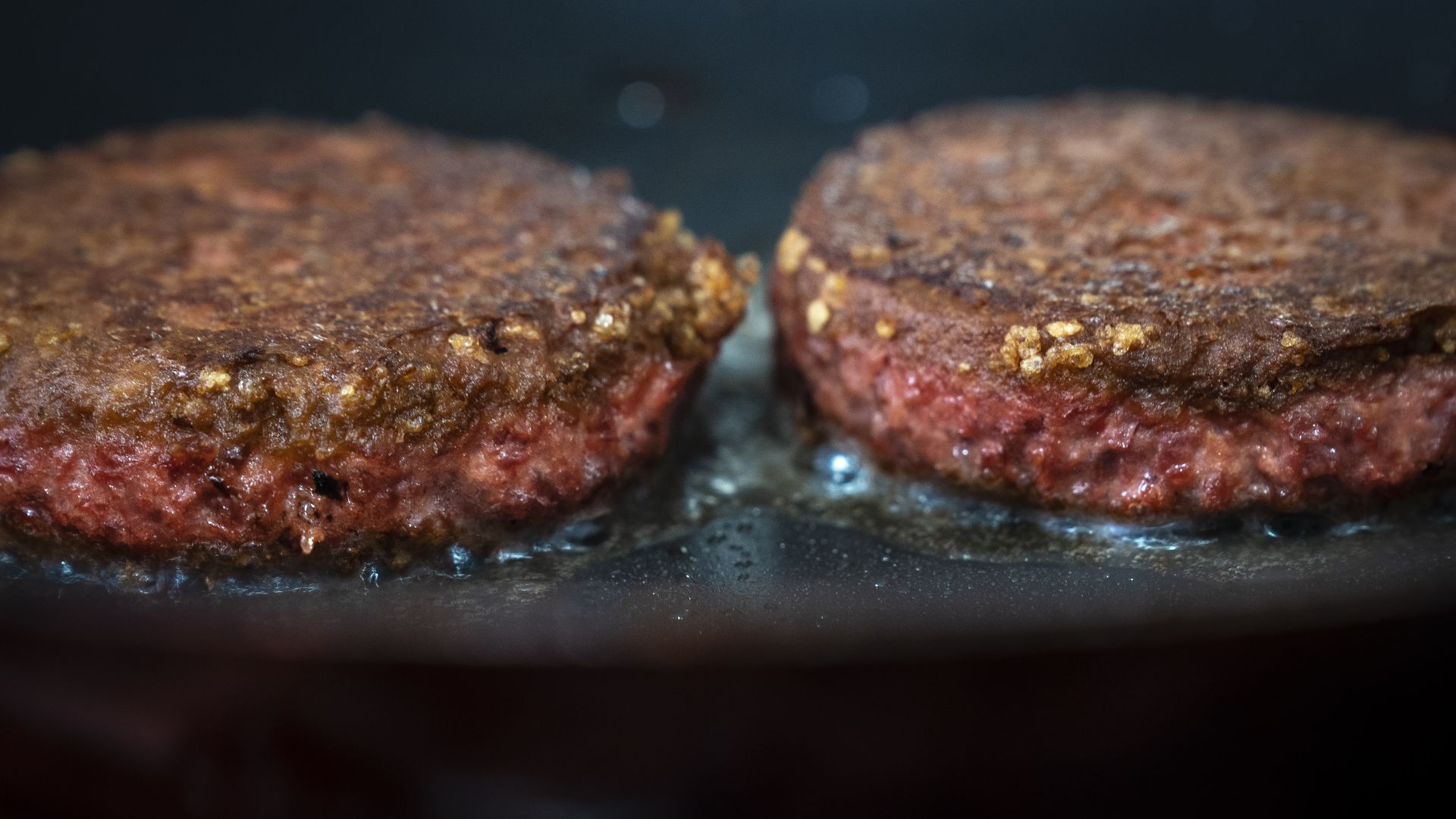 Photo of Beyond Burgers frying in a skillet.