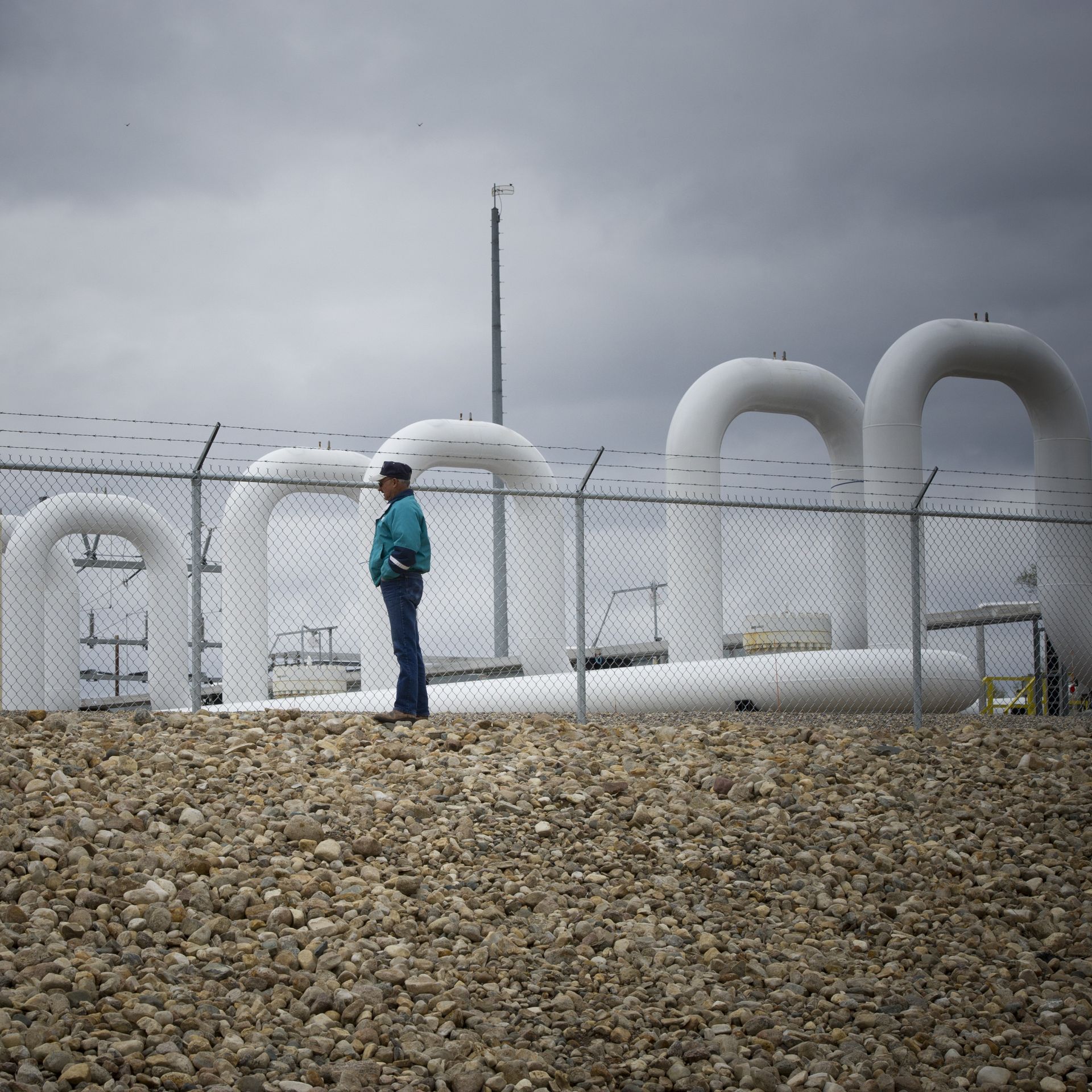 man stands in front of white pipes at oil pumping station