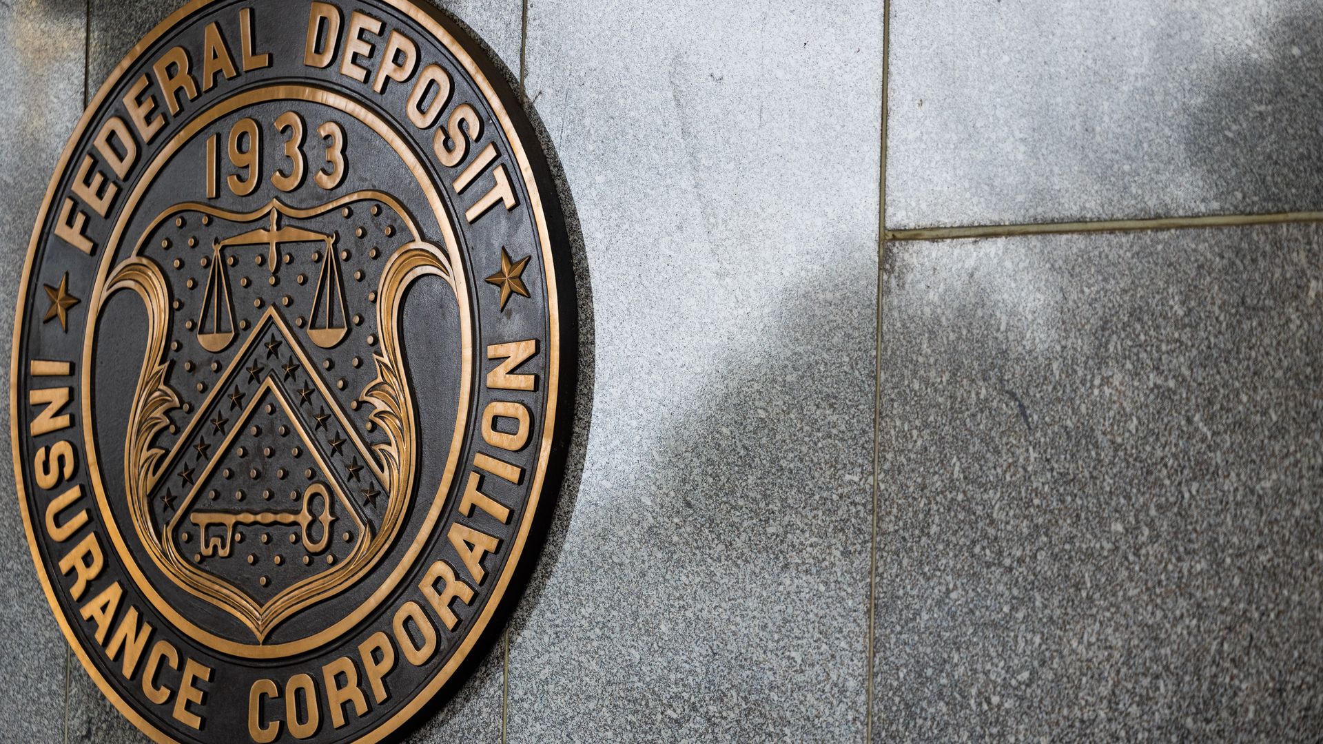 A gray marble wall with a giant logo for the Federal Deposit Insurance Corporation.