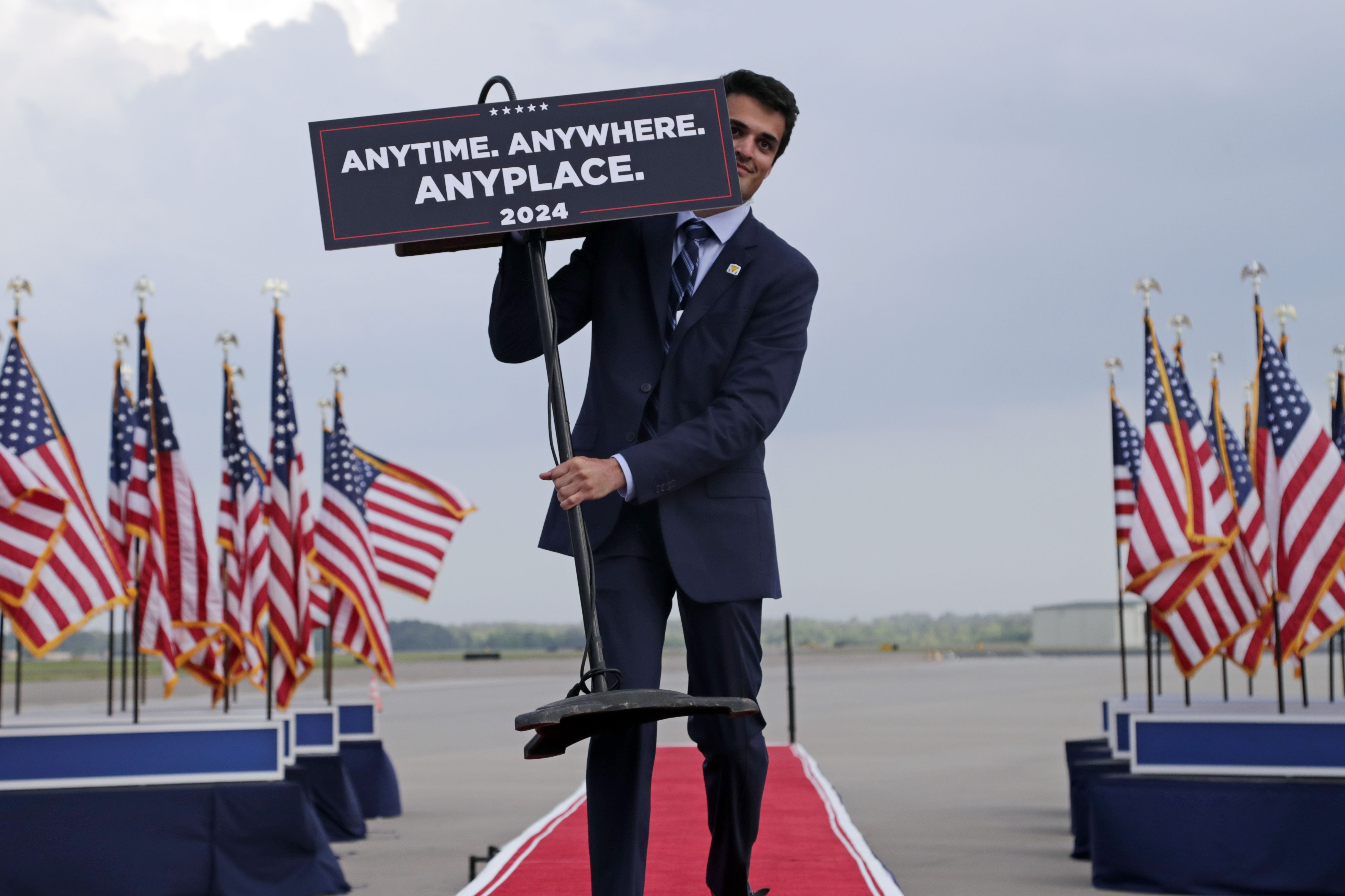A campaign worker carries out a podium that indicates former President Donald Trump will debate President Joe Biden anytime, anywhere or anyplace, before Trump speaks at a rally in Wilmington, N.C.