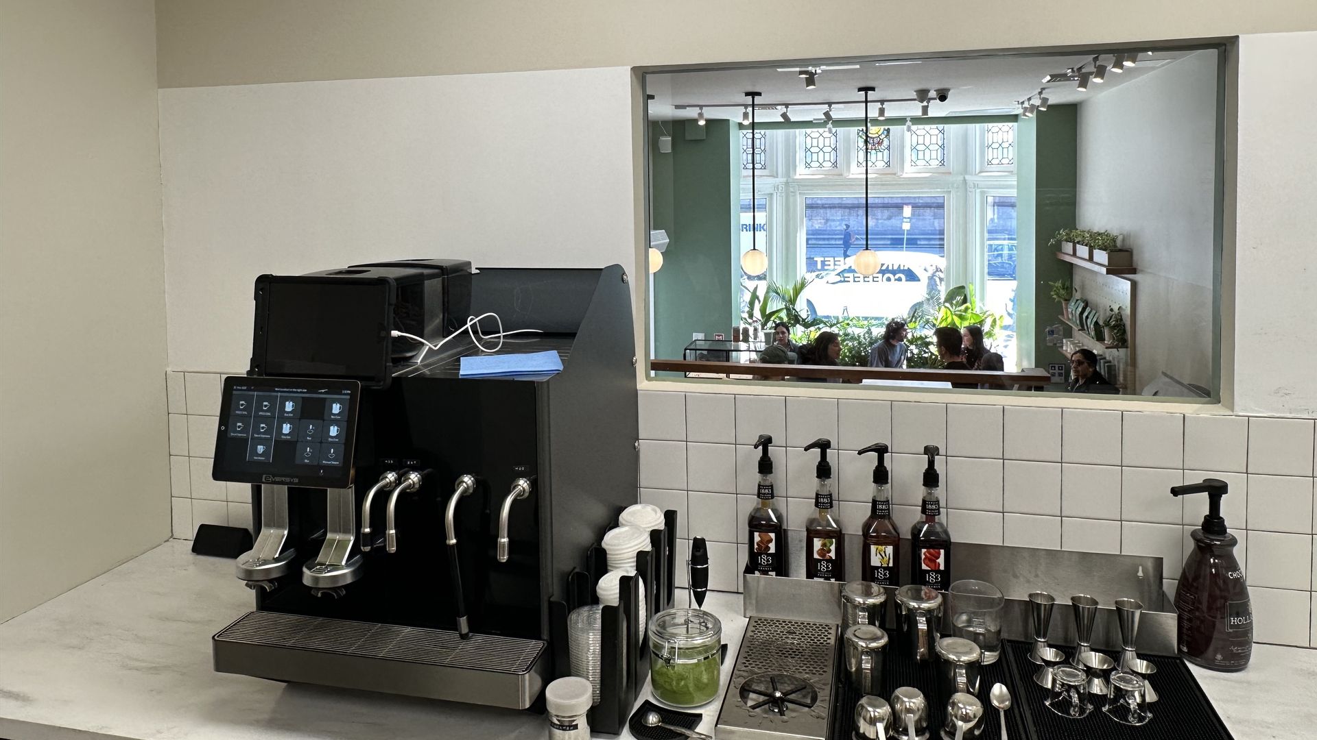 The Eversys espresso machine sits on the left of the counter with cups, lids and syrups to the right in Blank Street's barista training lab.