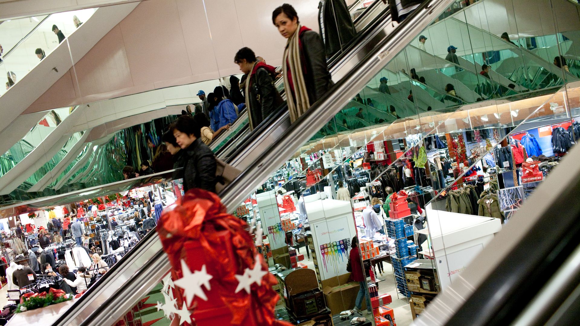 Last-minute shoppers are reflected in the side of an escalator in a Macy's department store at Tysons Corner Center, a mall in suburban Washington, on Christmas Eve on December 24, 2008