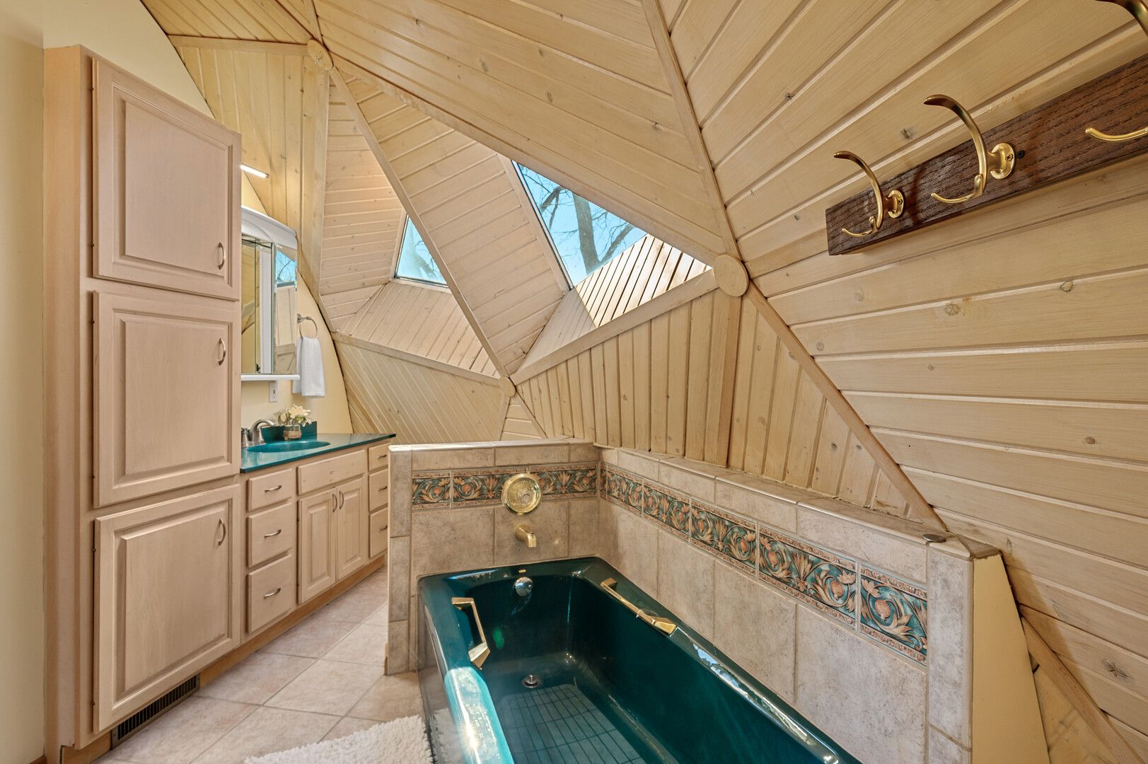 A bathroom with wood walls and a green tub.