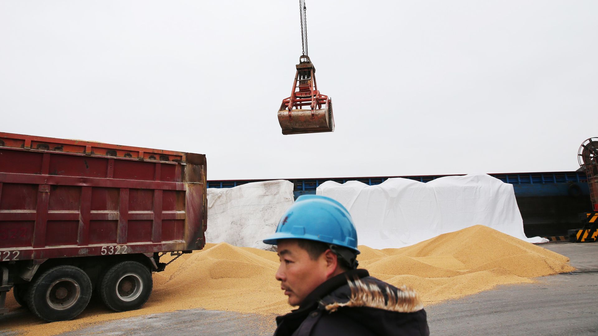 Man looks on as cargo lowered from ship