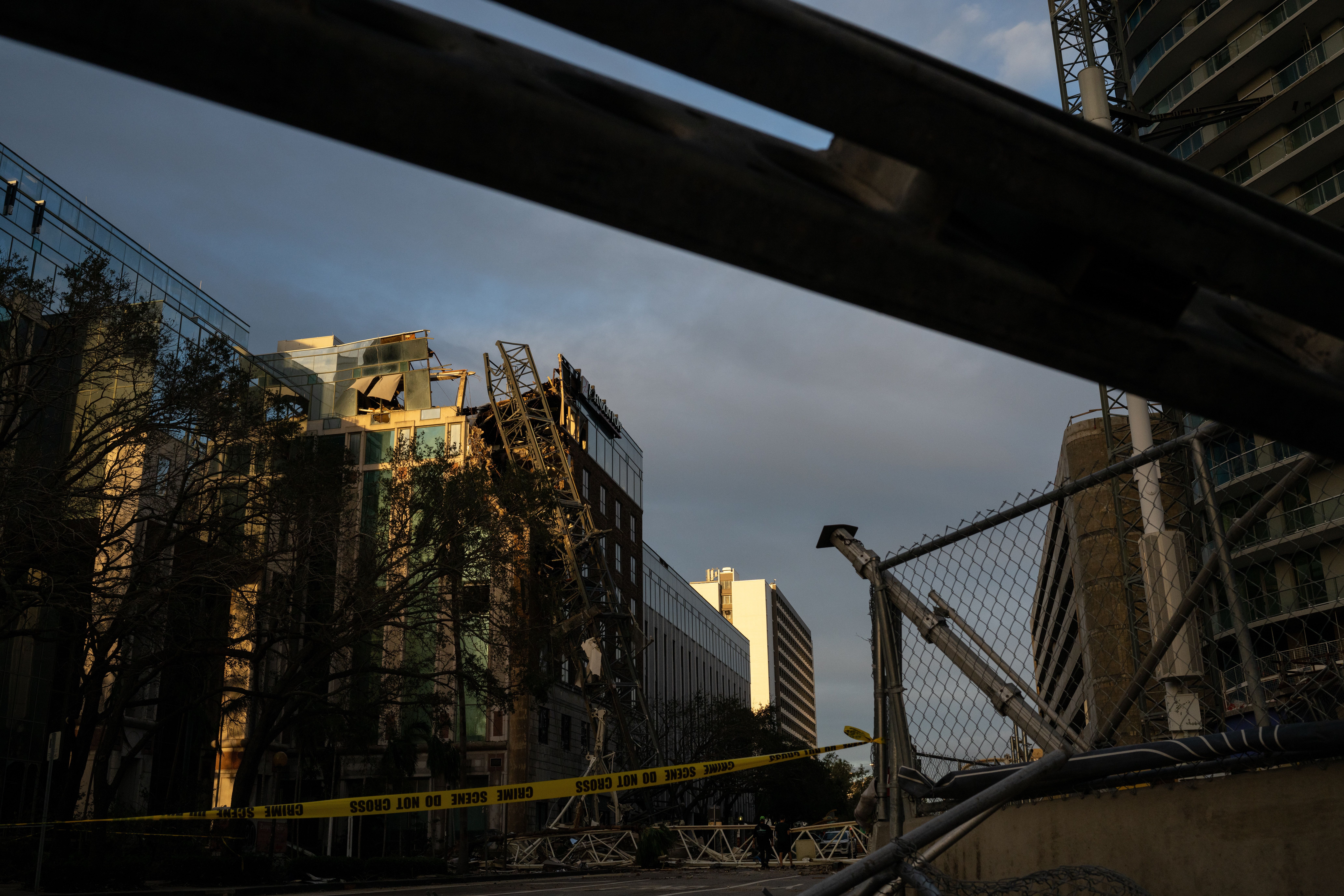 A crane leaning against a heavily damaged building.