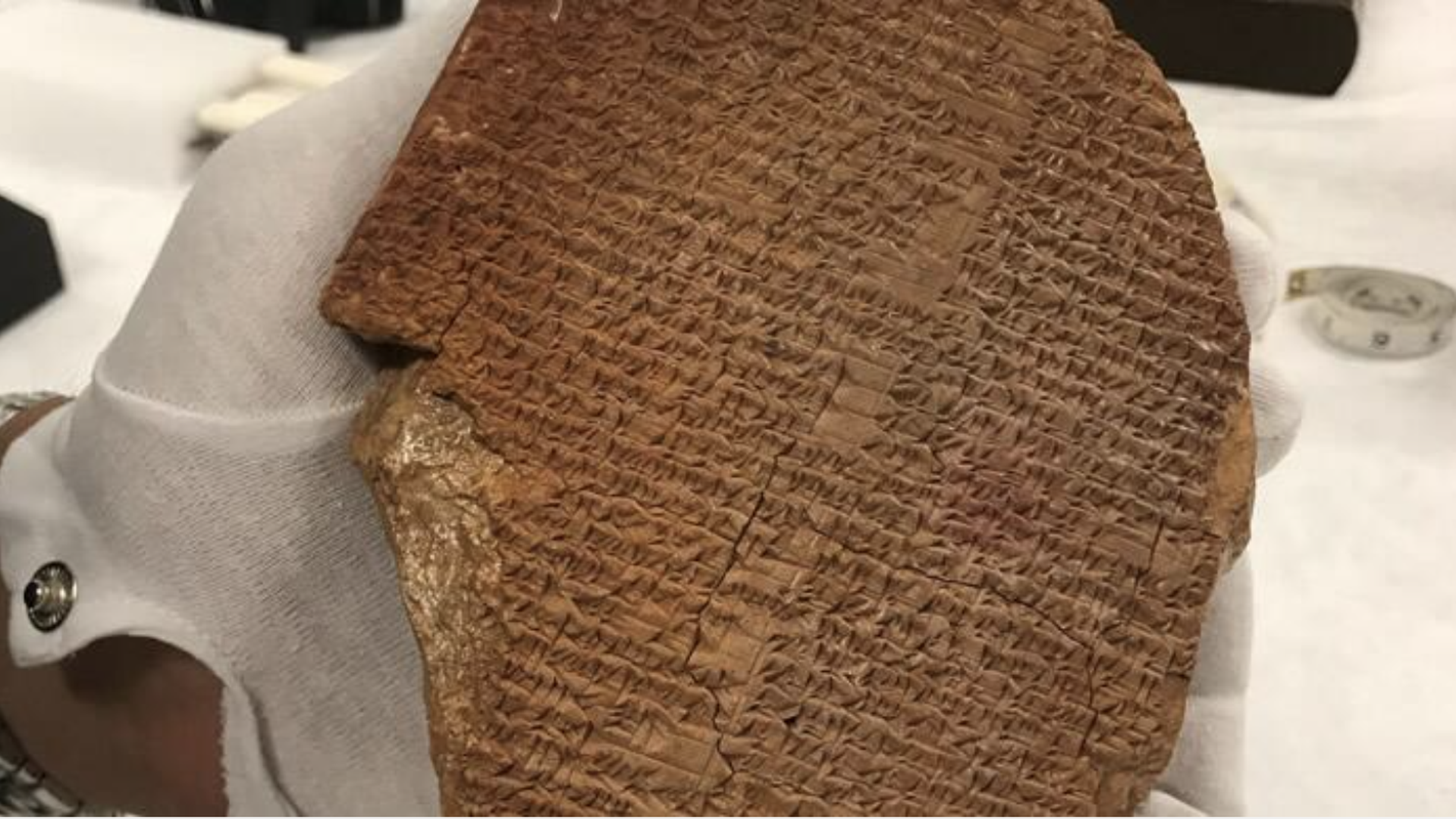 A gloved hand holds the tablet 