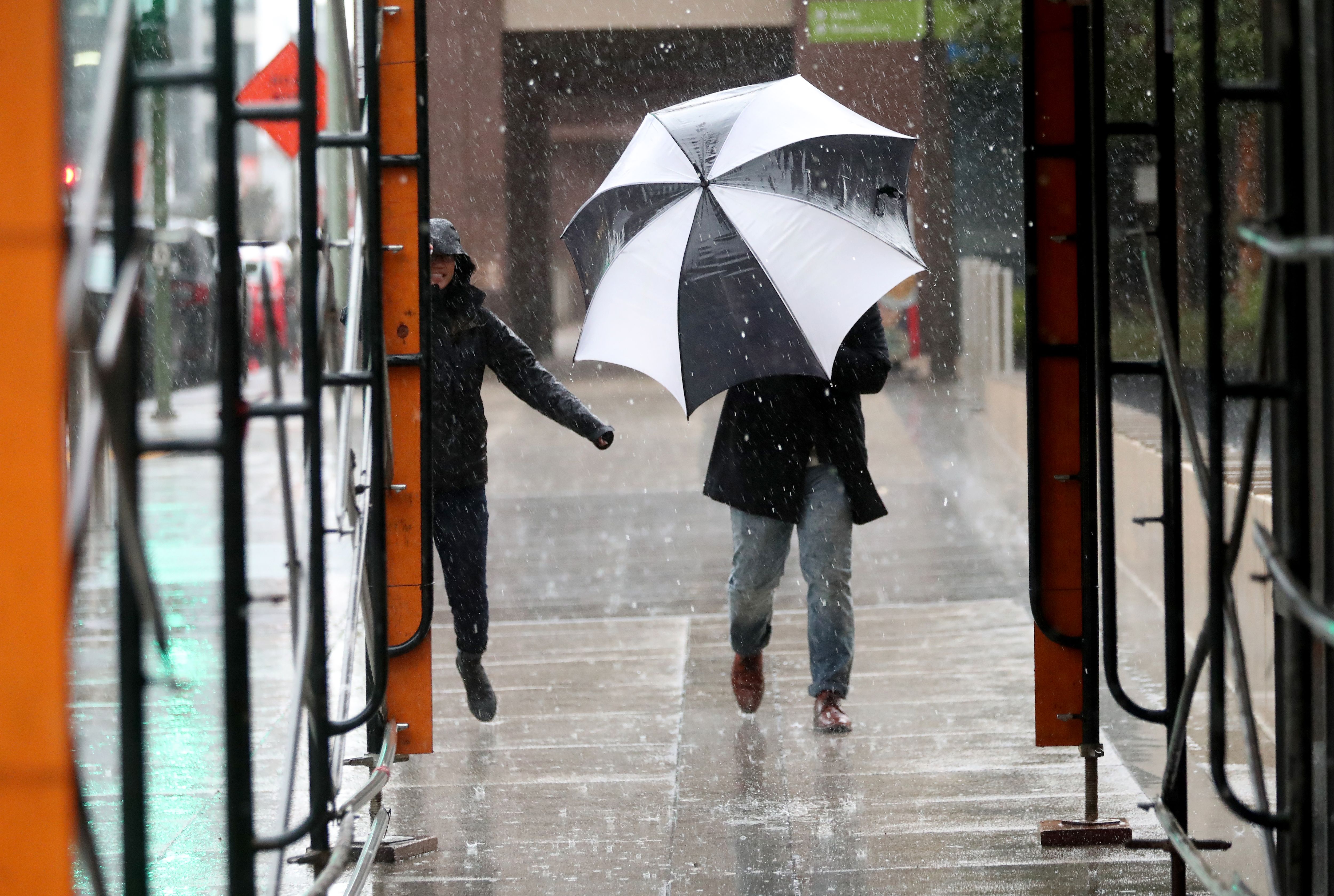  People fight the wind and rain as they walk along 12th Street near Broadway in Oakland, Calif.