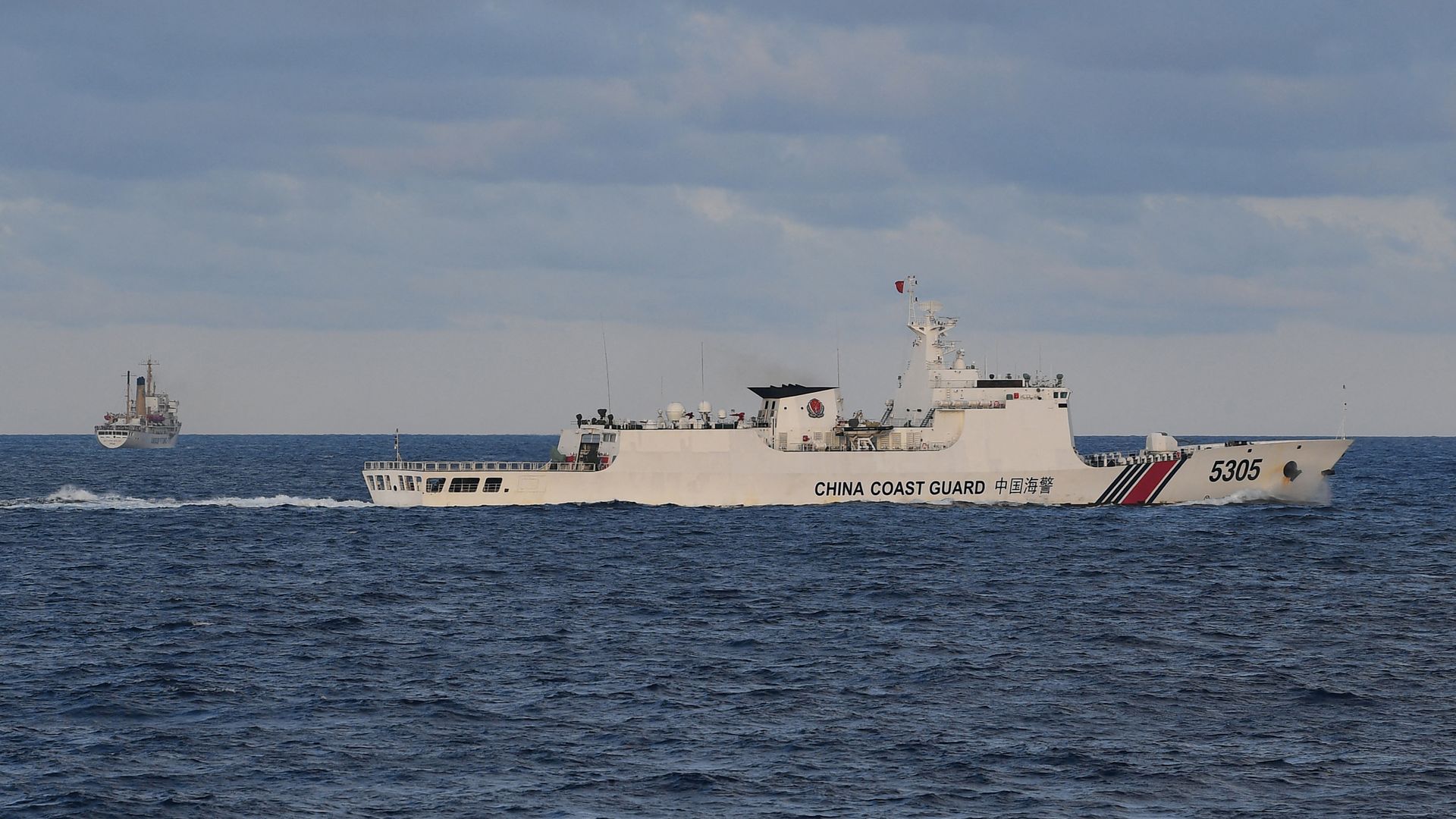 This photo taken on December 10, 2023 shows a Chinese coast guard ship shadowing a Philippine vessel (L) loaded with provisions for Filipino fishermen and troops in disputed waters of the South China Sea.