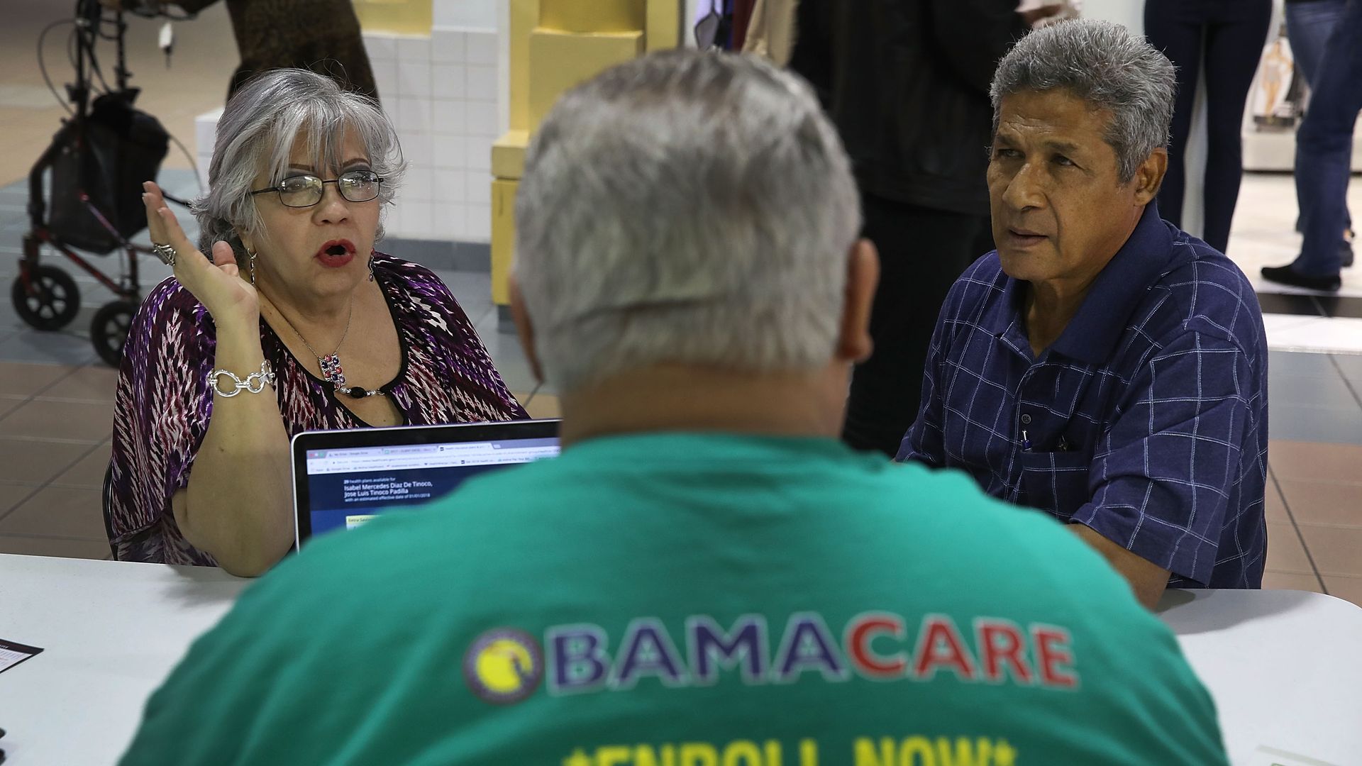 A man helps two Florida residents sign up for insurance under Obamacare