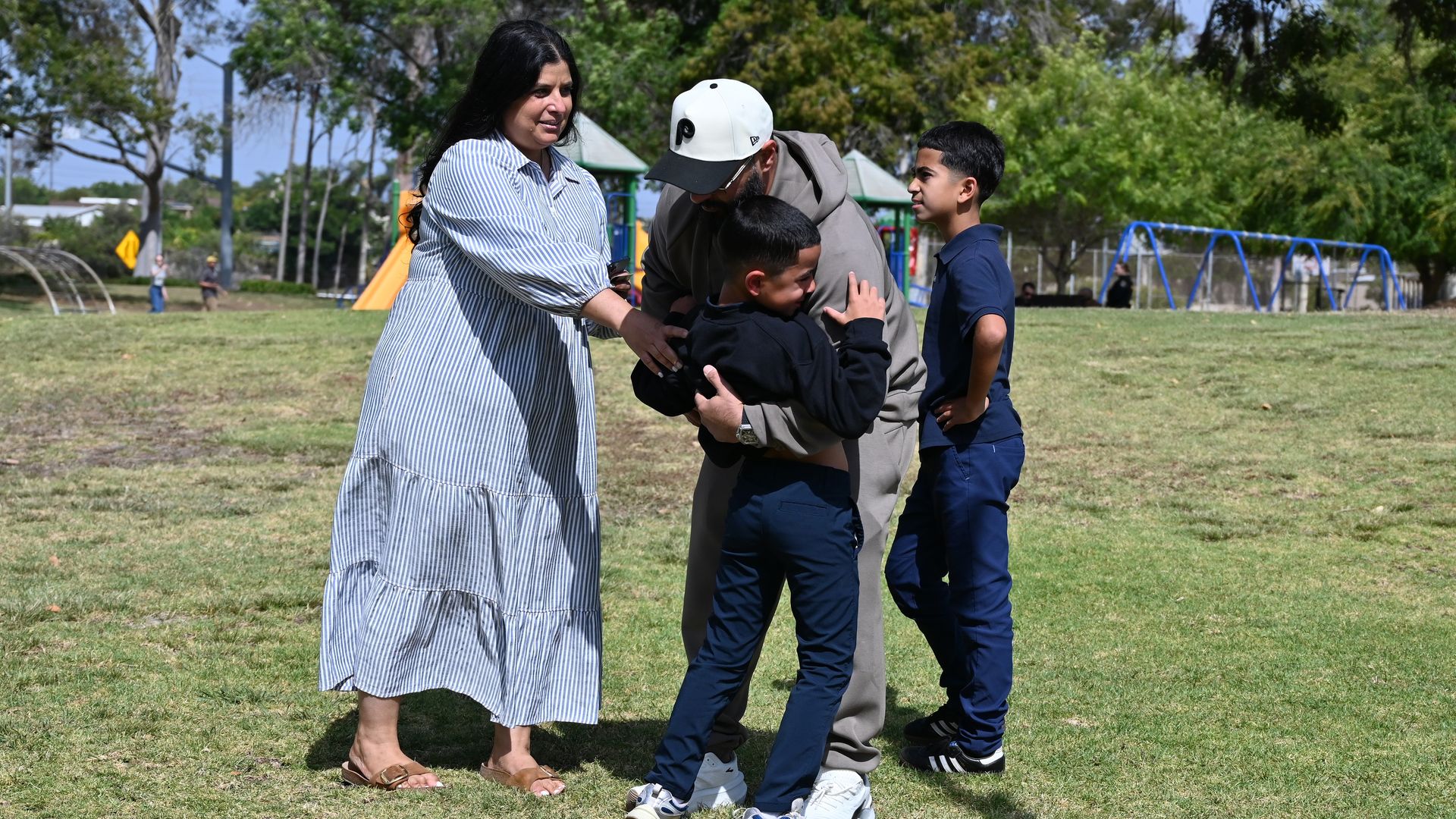 SAN DIEGO, CALIFORNIA - MAY 18: A family reunites with loved ones at the corner of Lindbergh Park next to the crime scene as law enforcement and emergency services respond to a shooting at the Islamic Center of San Diego (ICSD) on May 18, 2026 in San Diego, California