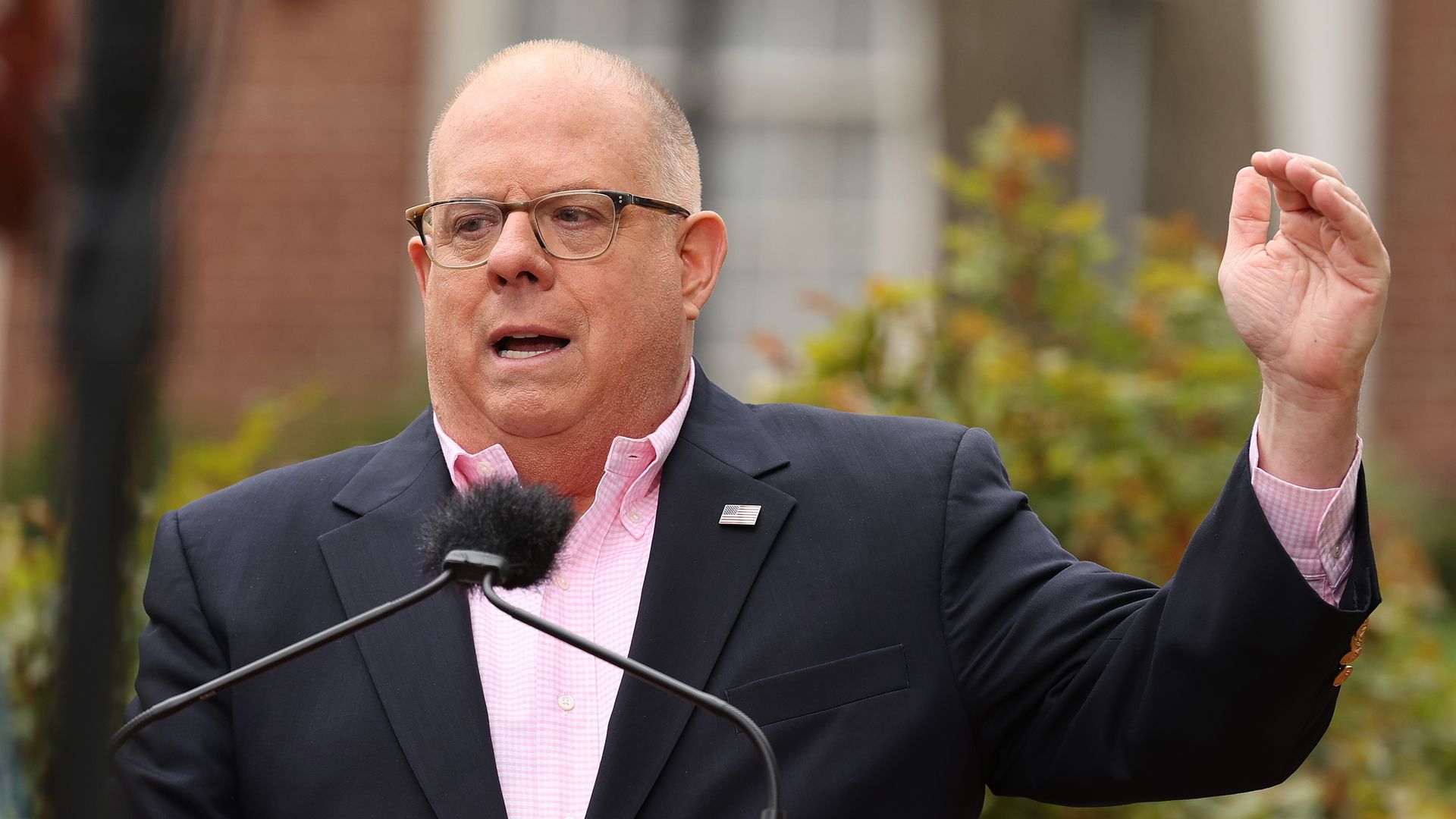 In this image, Hogan stands and speaks