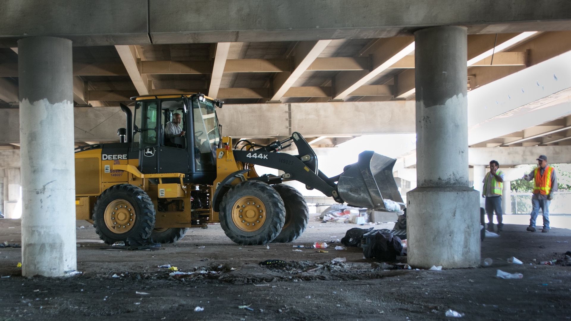 A bulldozer clears out debris from a tent encampment