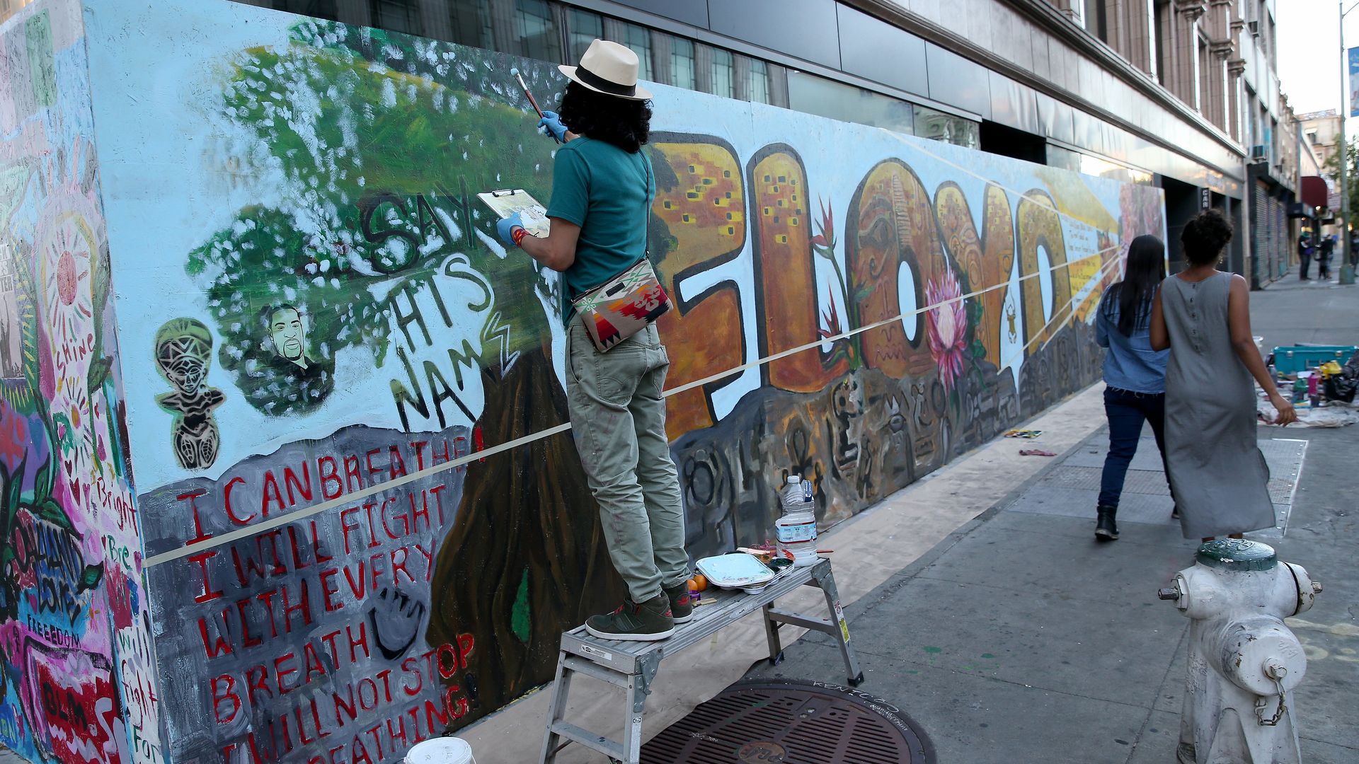 Octavio Hernandez, left, and other artists from the People's Conservatory, work on a mural for George Floyd on 15th Street in downtown Oakland