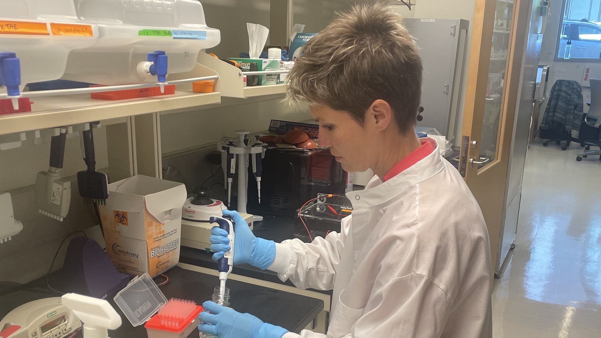 A scientist in a white lab coat conducts an experiment in a lab. 