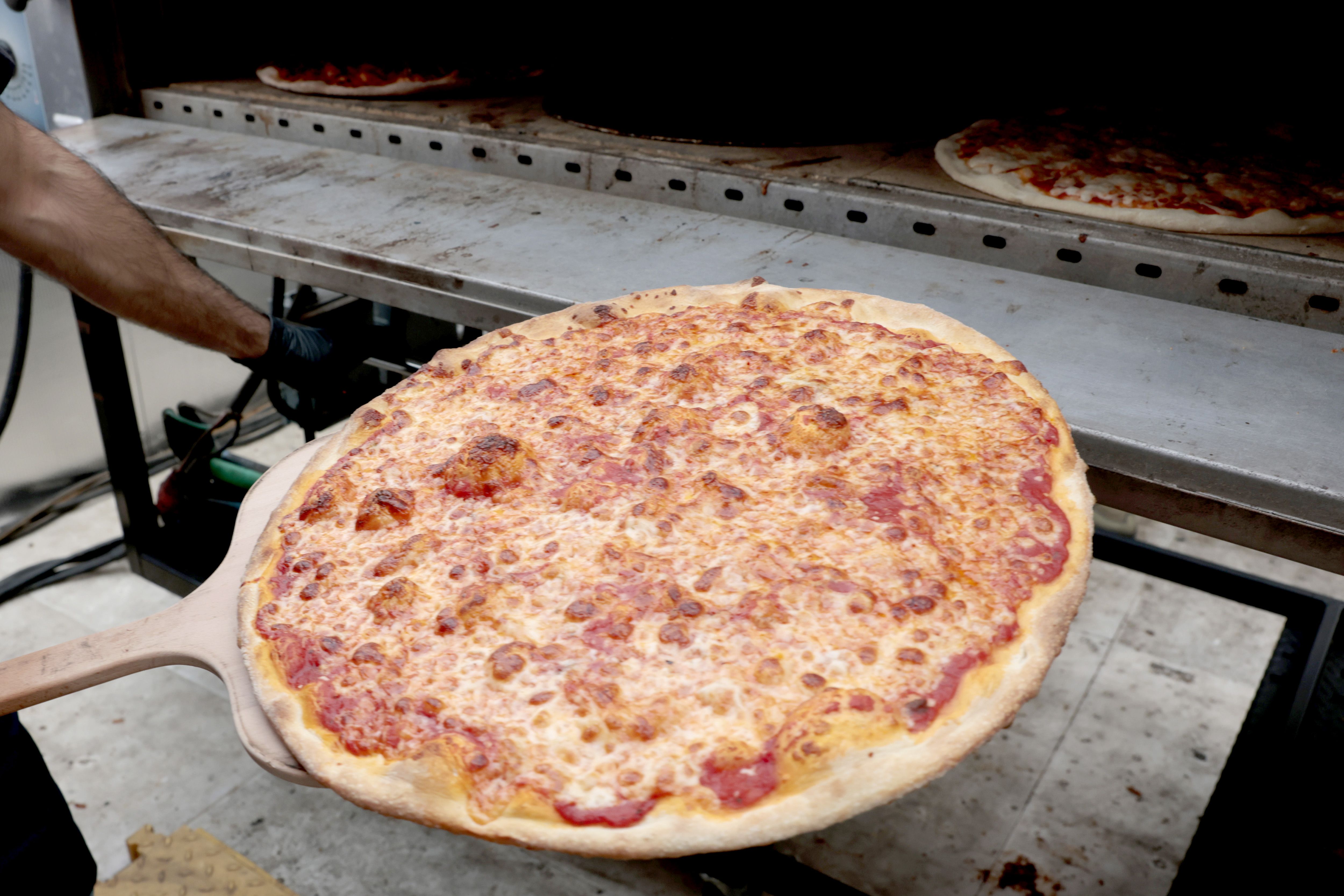 A whole pizza goes into an oven