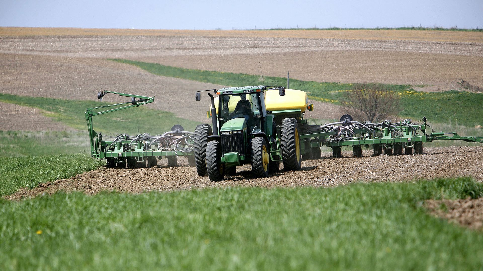 Pulling a corn planter behind his John Deere tractor, a farmer in Wisconsin.