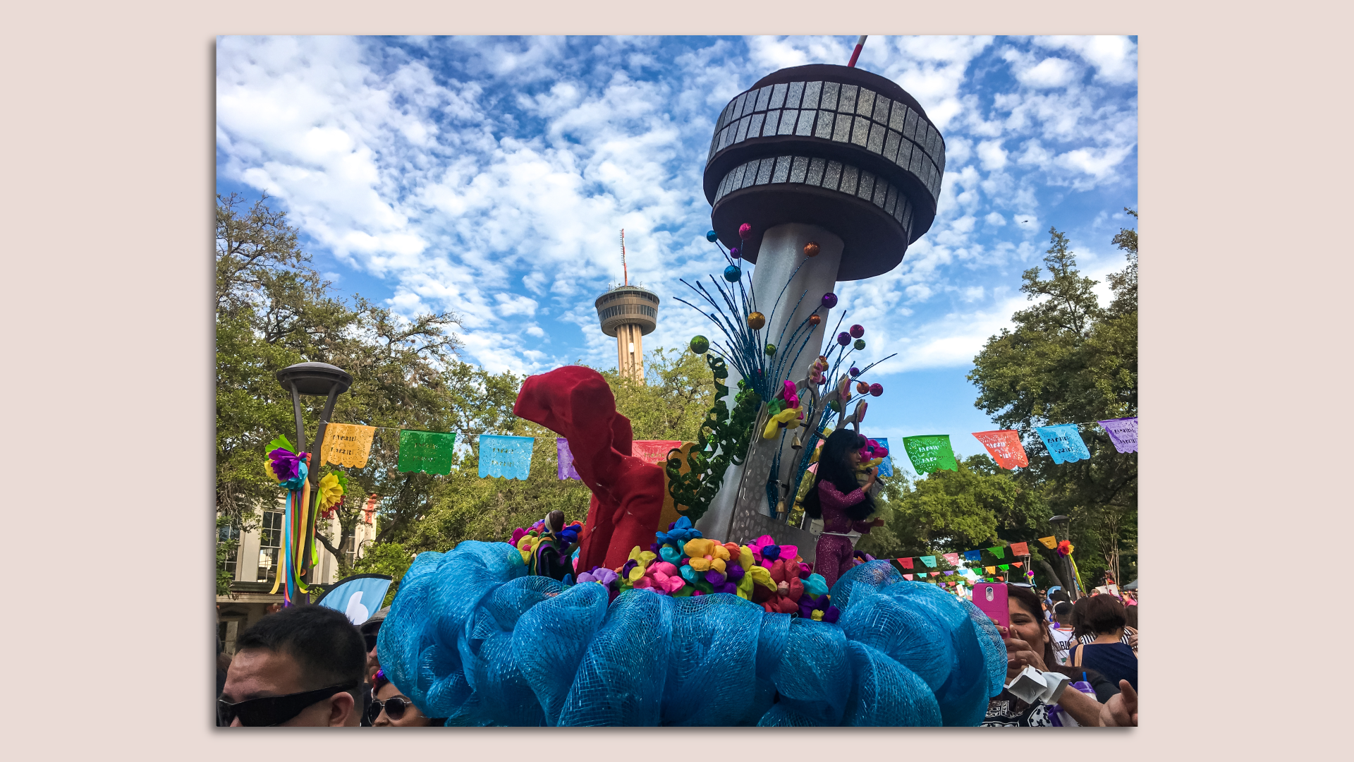 A Fiesta hat topped with a model version of the Tower of Americas is in front of the actual building. 