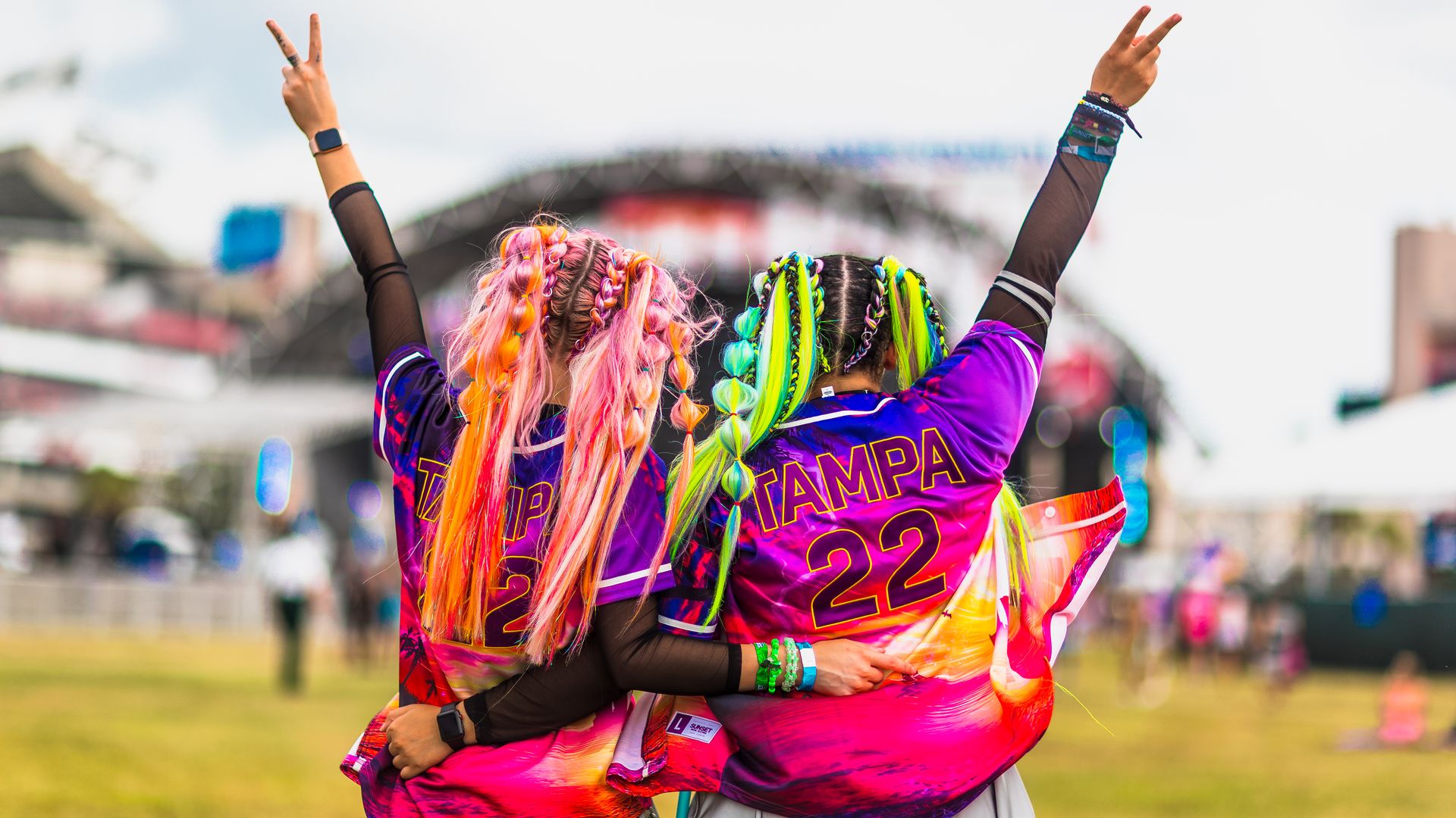 two people with colorful hair flash peace signs wearing "tampa 22" jerseys