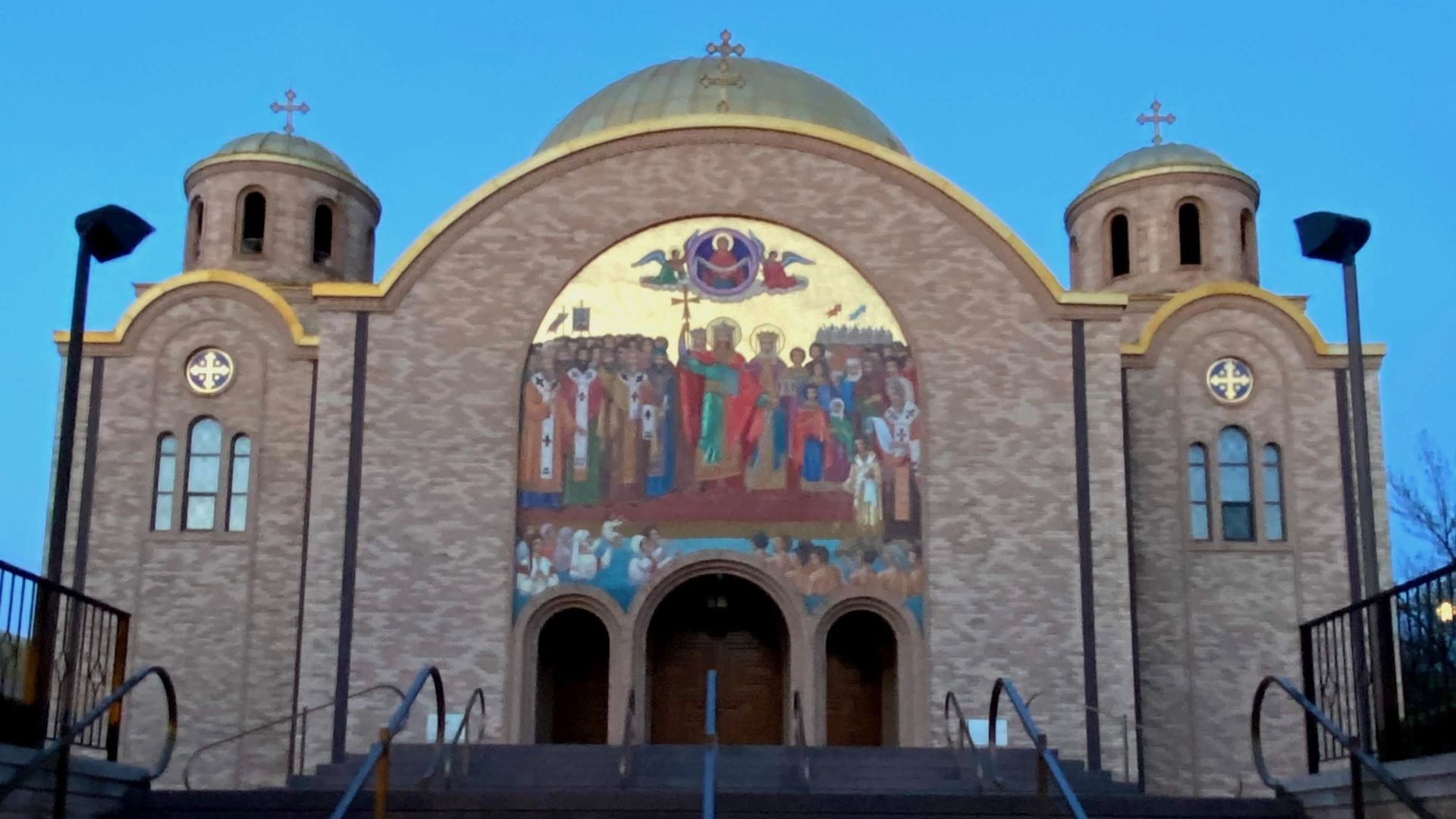 Church with two towers and arched tops in front of a blue sky.