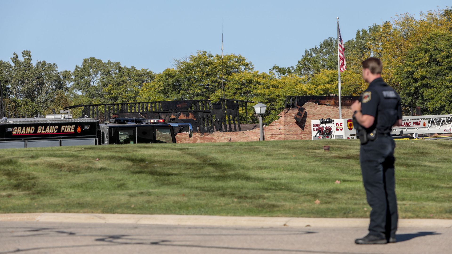A public safety official stands in front of the burned church, with an american flag visible