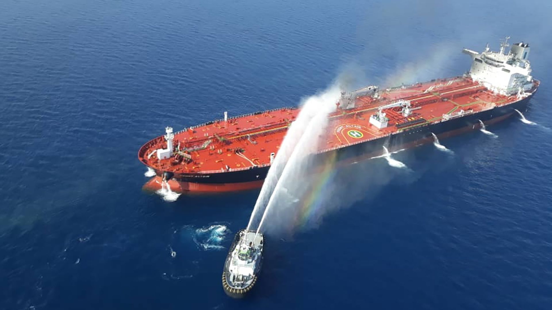 This image is a birds eye view of an oil tanker being sprayed with water from a smaller boat.