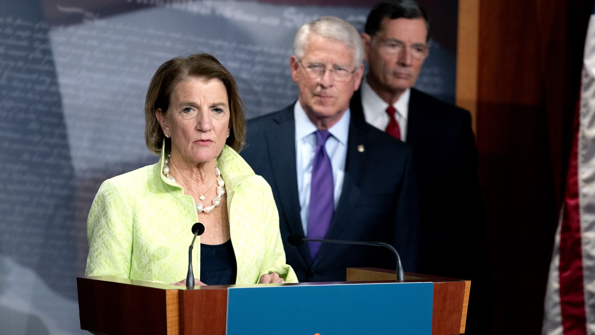 Lawmakers at a podium.