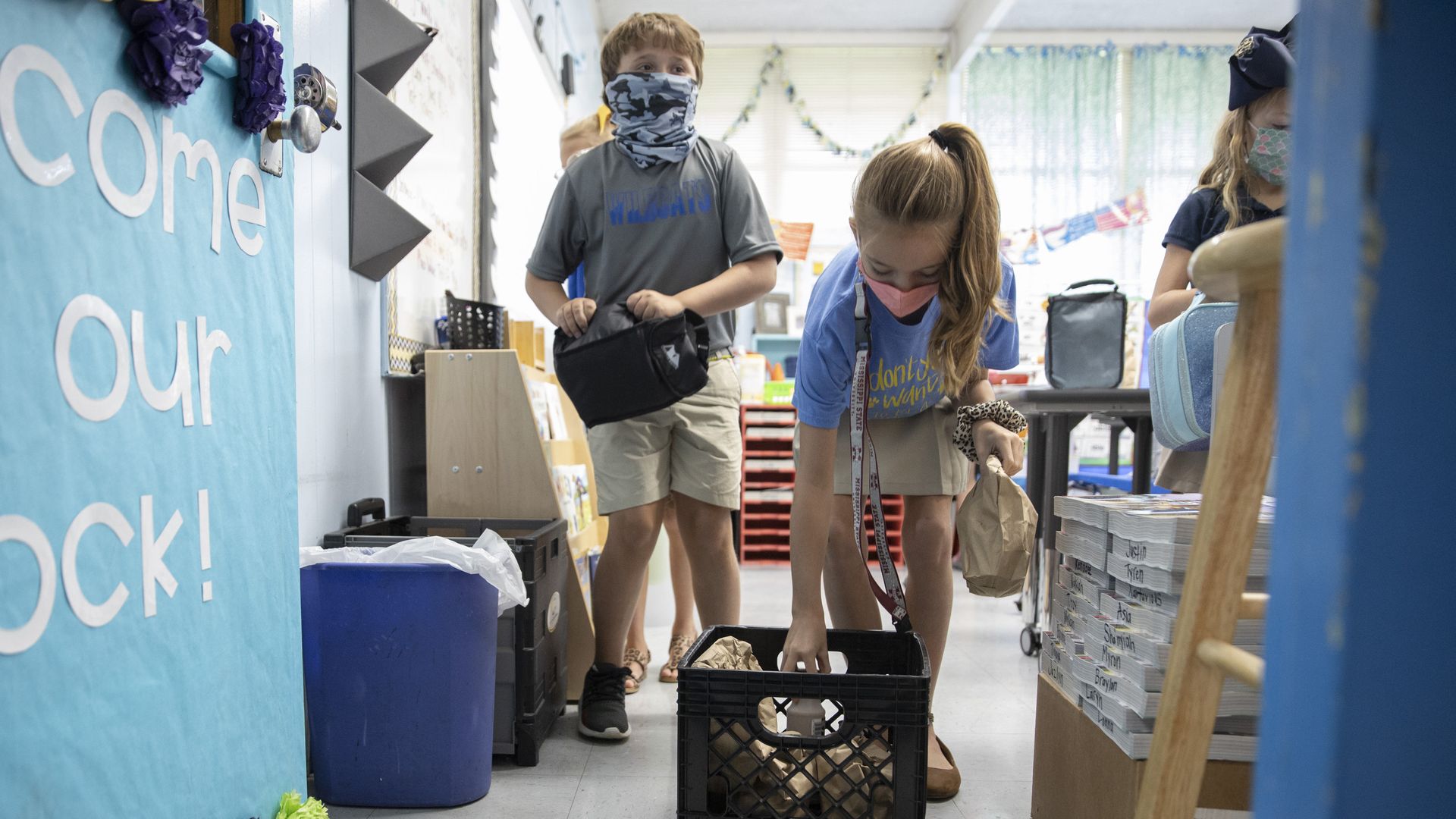 Children retrieve bagged lunches in their classroom