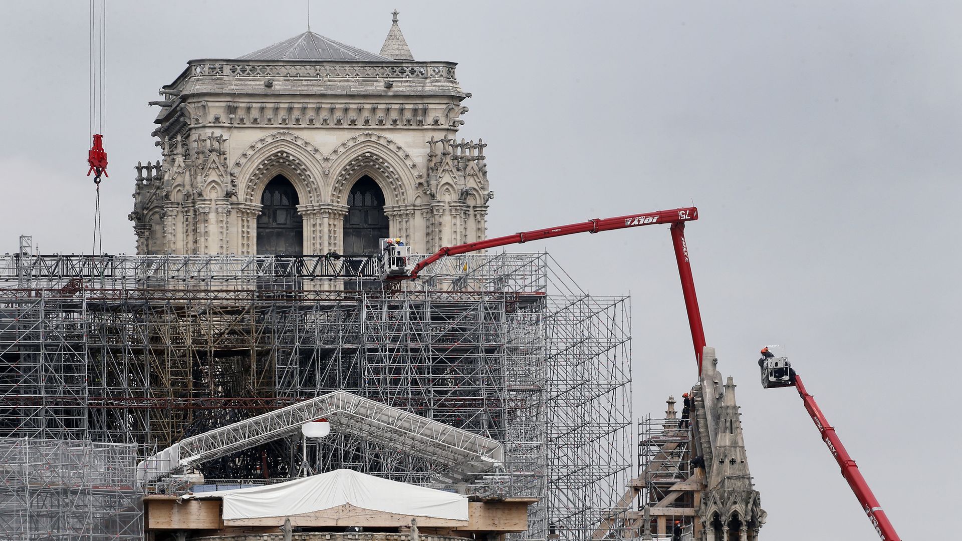 Professional mountain climbers wearing protective face masks work on a part of Notre Dame Cathedral