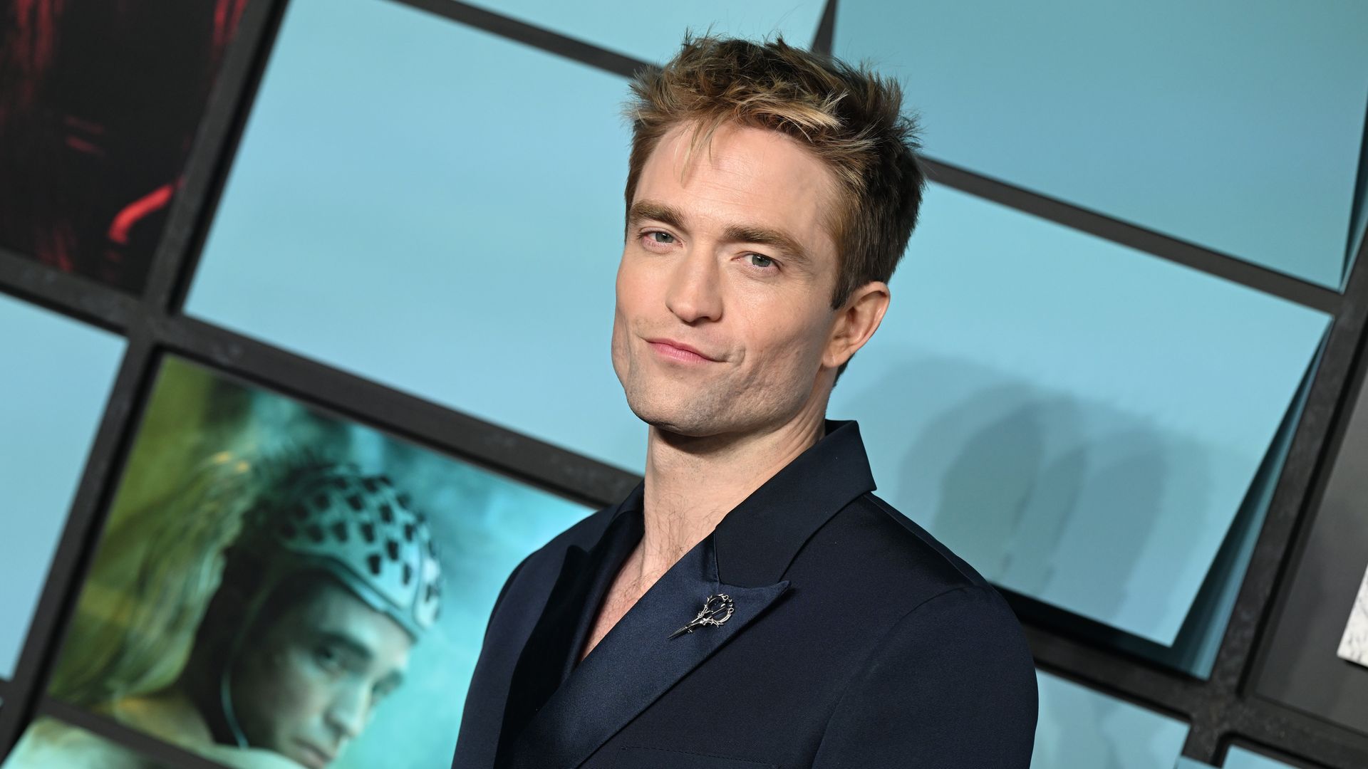 Photo shows a headshot of Robert Pattinson in a suit.