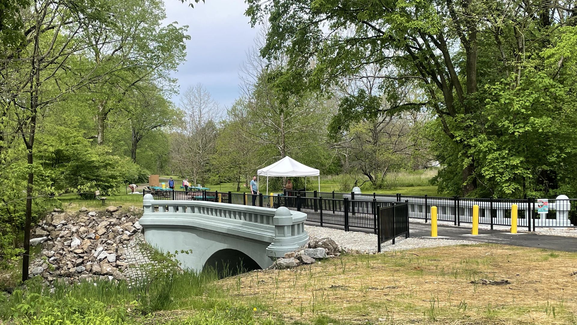 A pedestrian bridge. Surrounded by grass and trees.