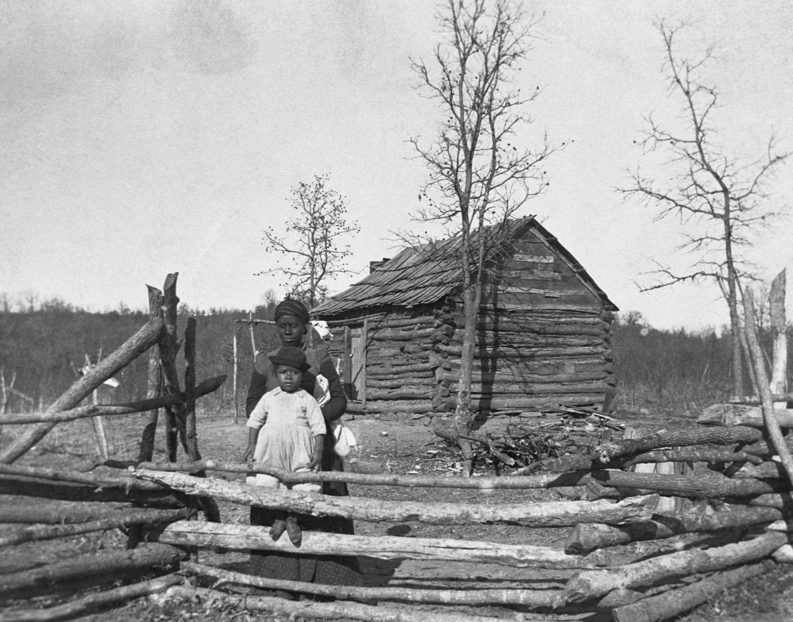 A mother and child in front of a home of Creek Freedmen in 1900.