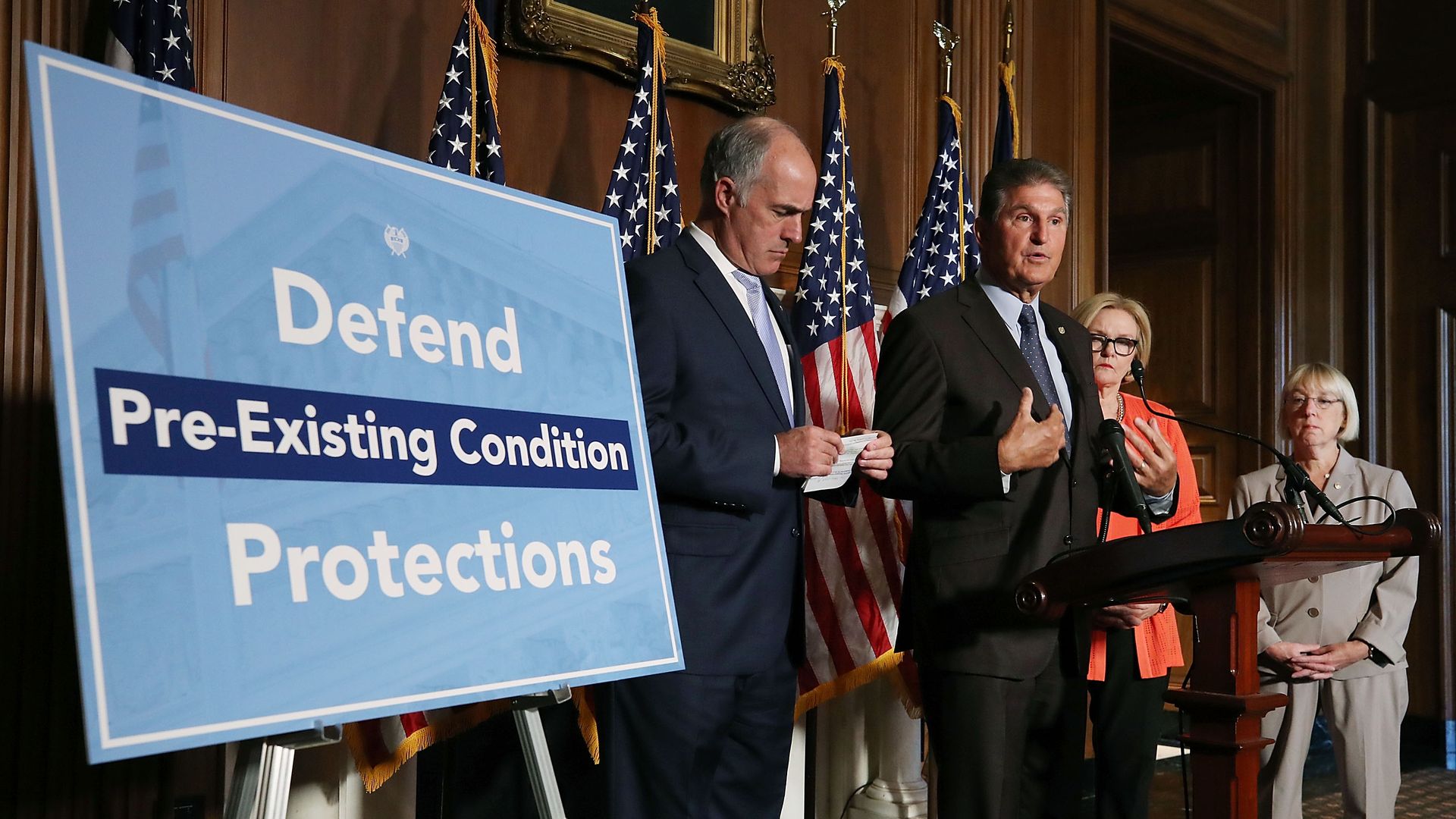 Sen. Joe Manchin (D-WV) with a big sign that says Defend Pre-Existing Conditions