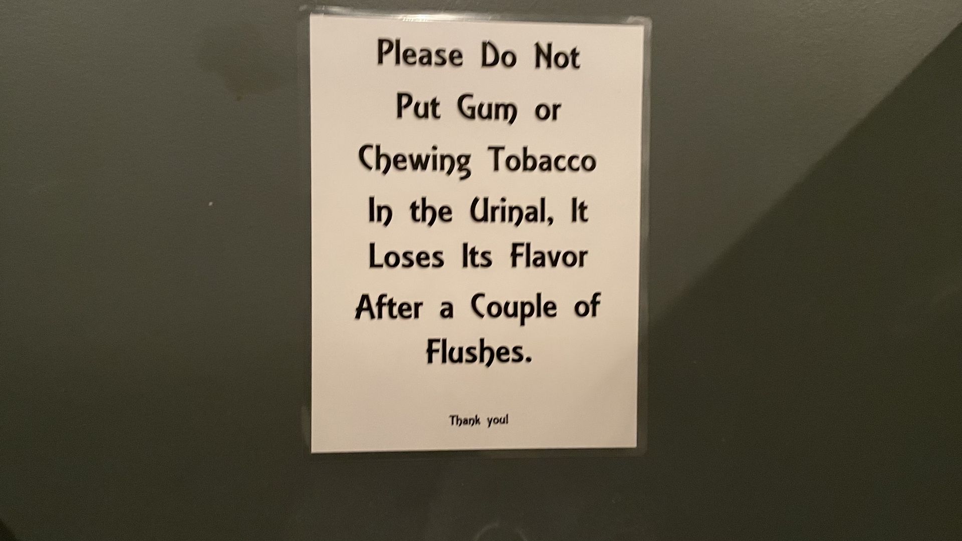 A photo of a funny message above a urinal.