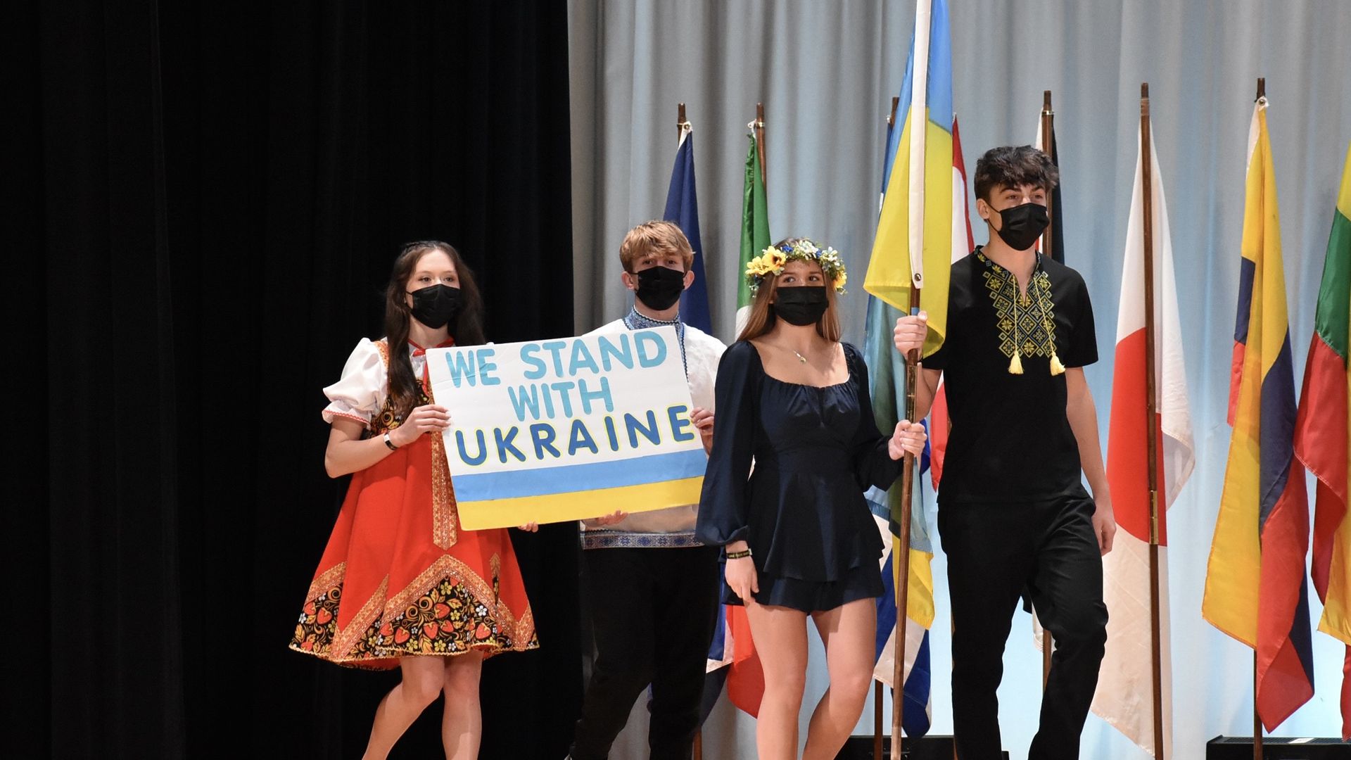 Students walk on stage with Ukrainian flag