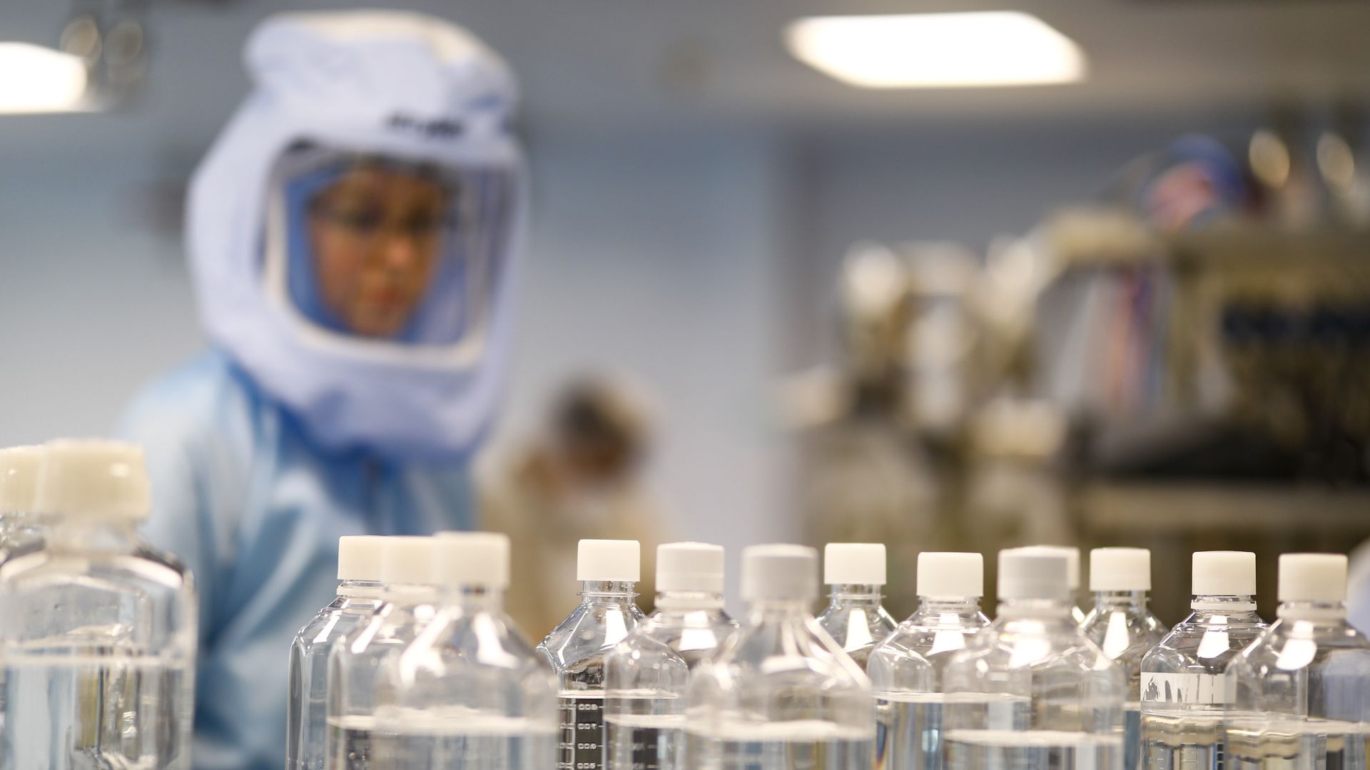 An employee wearing a lab suit tests procedures for mRNA for COVID-19 vaccine development. 