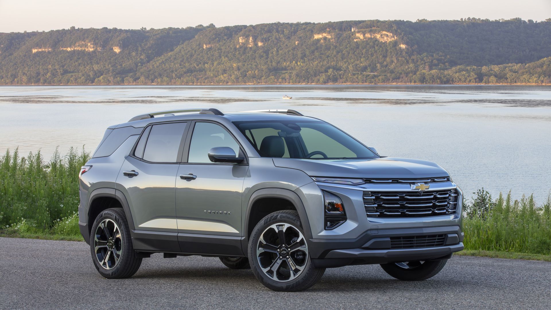 Front 3/4 view of a 2025 Chevrolet Equinox LT in Sterling Gray Metallic parked near a large body of water.