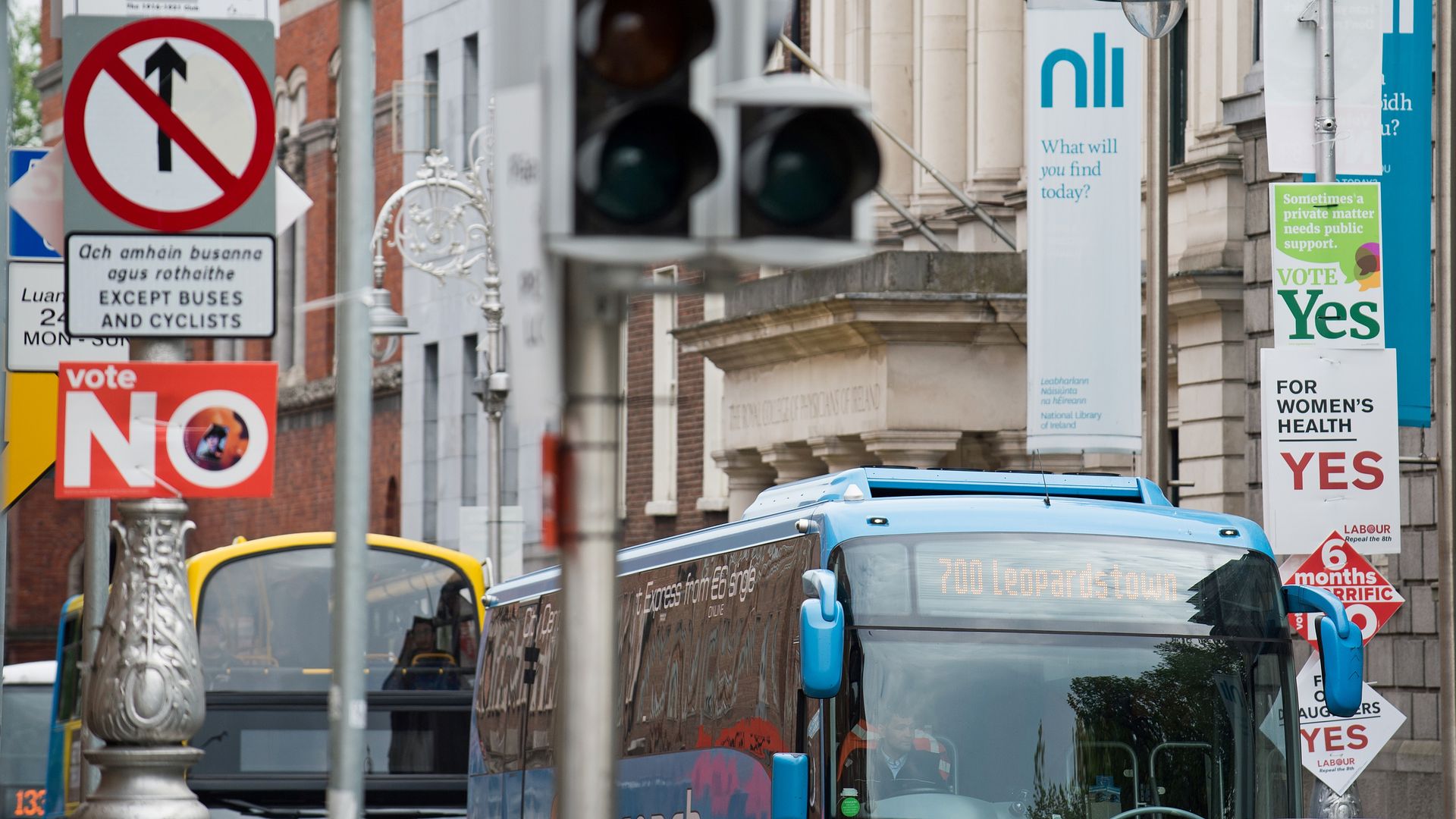 Buses pass posts covered in signs for anti- and pro-repeal of Ireland's abortion ban.