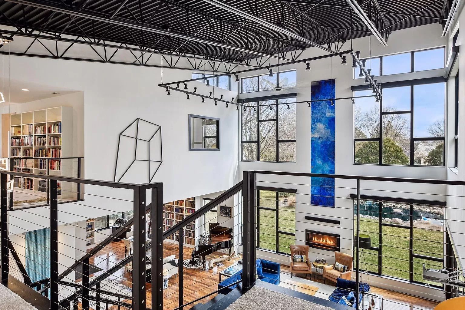 A living room as seen from upstairs with large windows and high ceilings.